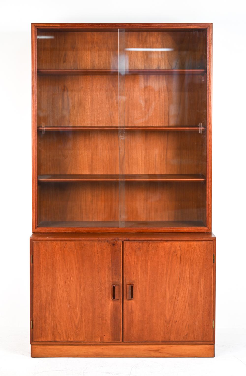 A fabulous high quality two-piece Danish mid-century bookcase or display cabinet in teak wood, designed by Børge Mogensen for the Danish manufacturer Søborg Møbler. This cabinet features adjustable shelves behind sliding glass doors and a bottom