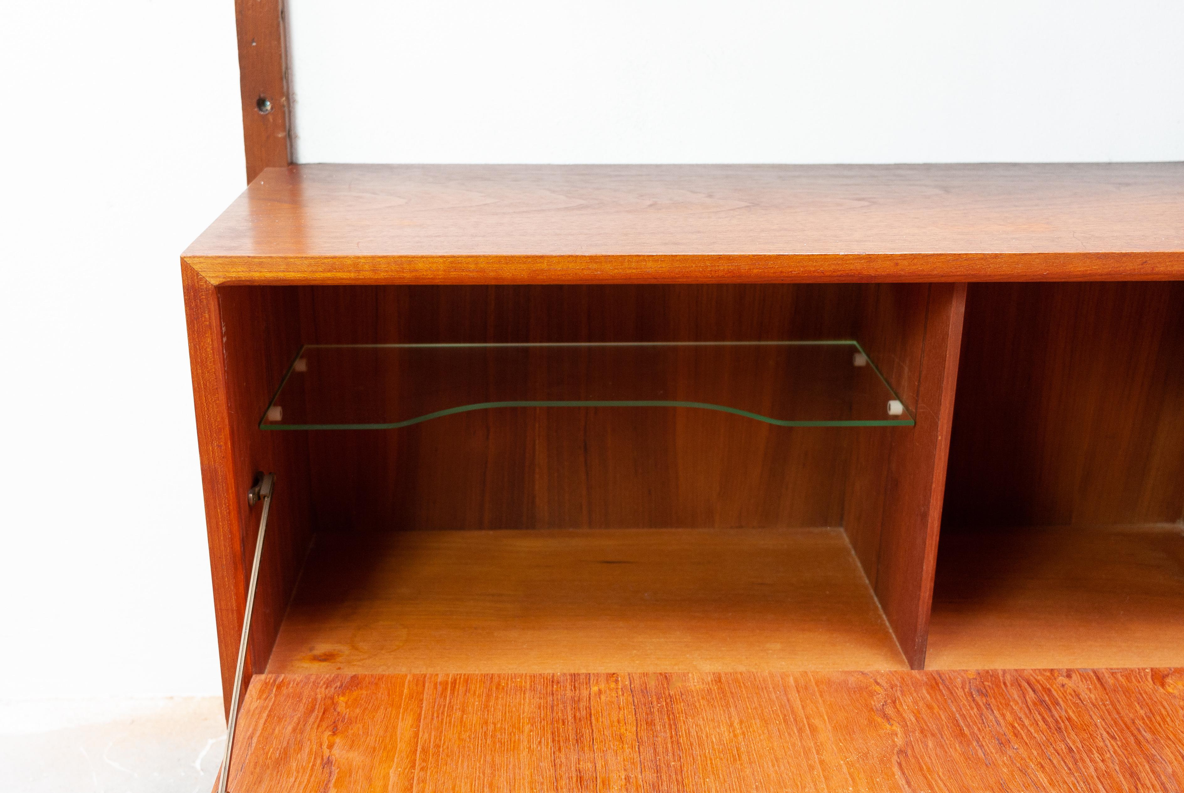 Teak modular hanging wall system. Design Poul Cadovius fot Royal Denmark, 1954. Consisting of,
Three wall units, six shelves, three glass shelves, three uprights, and all the metal hooks.
 