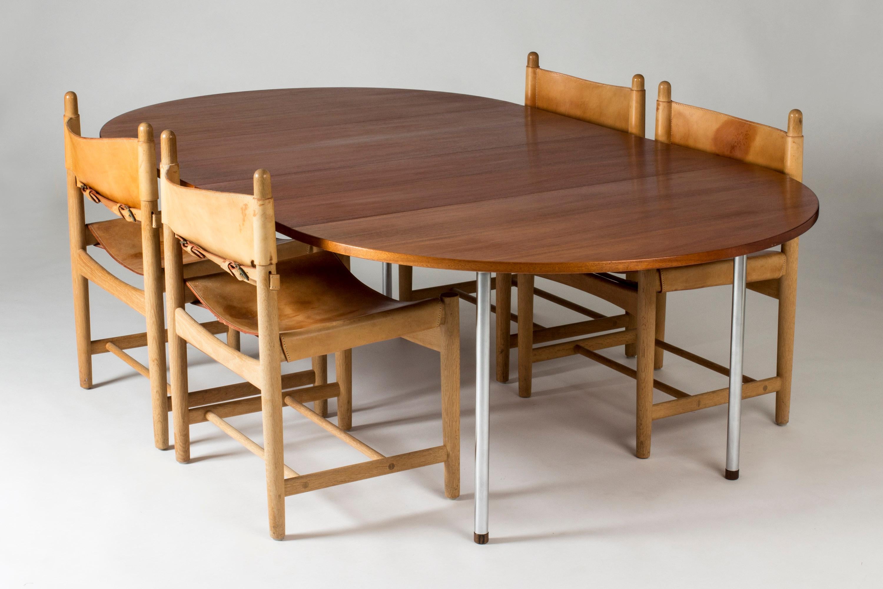 Teak dining table by Hans J. Wegner, in a sleek versatile design. The round neat size can be extended into a generous dining table seating ten people comfortably. Steel legs with wooden ends.