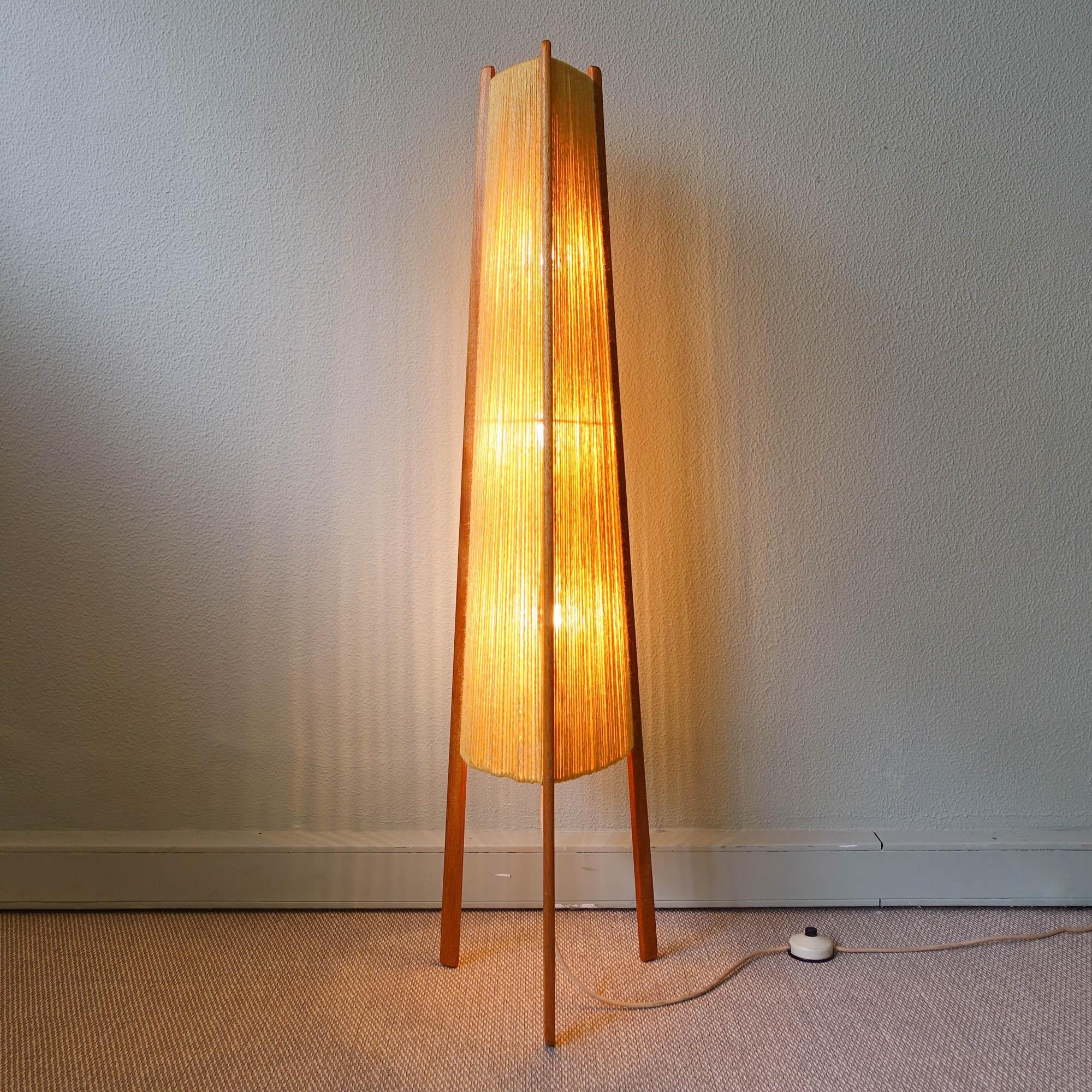 This floor lamp was designed and produced in Scandinavia during the 1960's. It features a structure with three teak legs that are screw to the lampshade. On the top is a teak handle that is hold on a brass stem that holds the 3 x E27 bulb sockets.