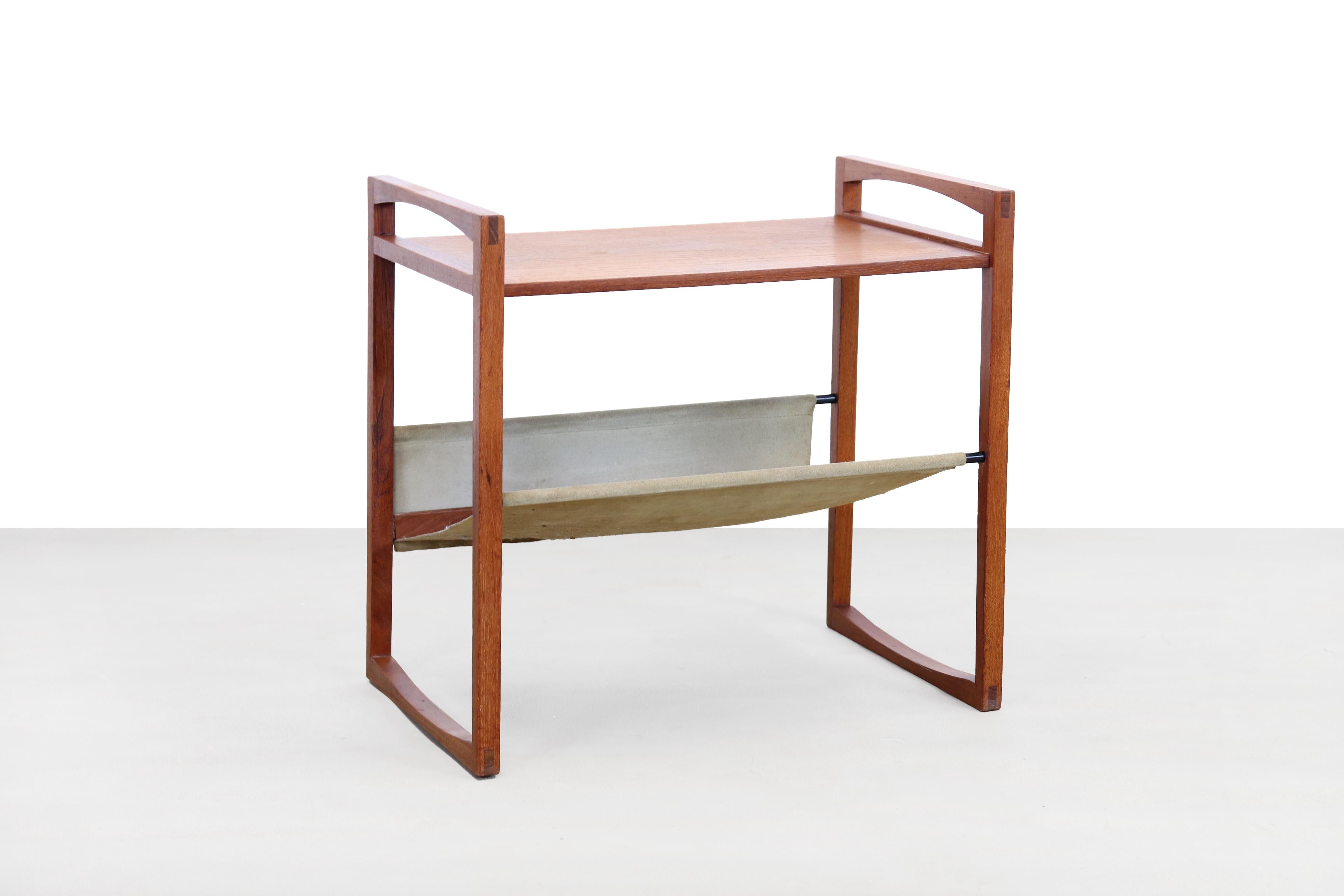Danish design magazine rack and side table designed by Kai Kristiansen for Sika Møbler. The bottom magazine compartment is made of suede. The table is made of solid teak and has beautiful details. For example, look at the wood joints in each corner.