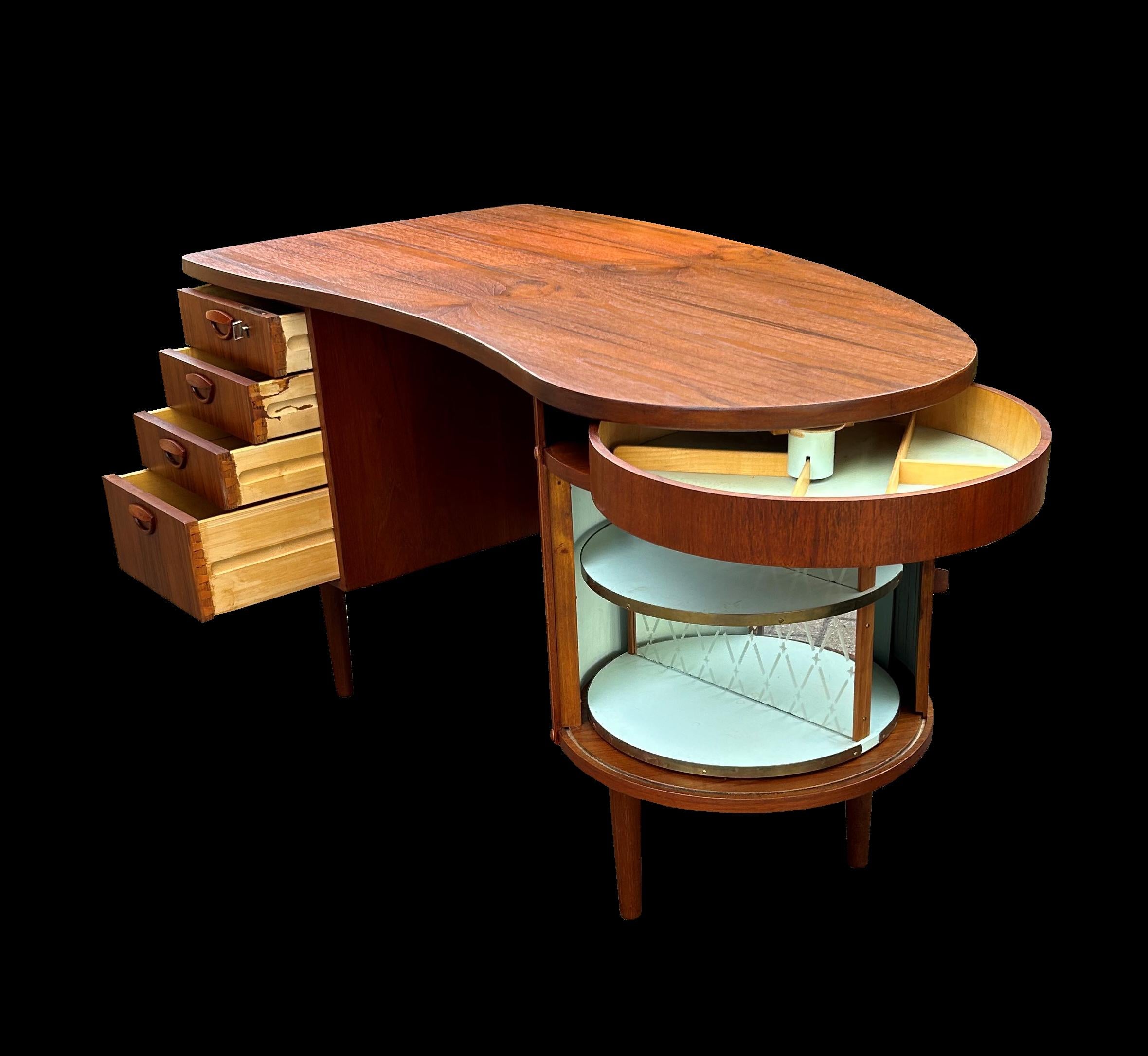 This is the kidney shaped desk with built in revolving cocktail cabinet behind a tambour slide, and 4 graduated drawers. On the back are open bookshelves.