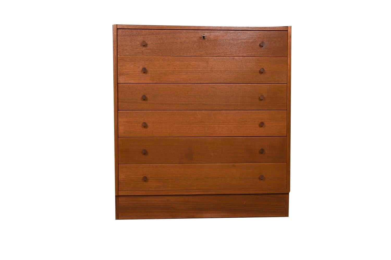 Mid-century modern teak tall dresser, chest of drawers, made in Denmark. Minimalist Danish Modern inspired profile and extremely well-made dresser, has incredible lines and detailing. Stunning teak grain tall dresser accented with sculpted teak