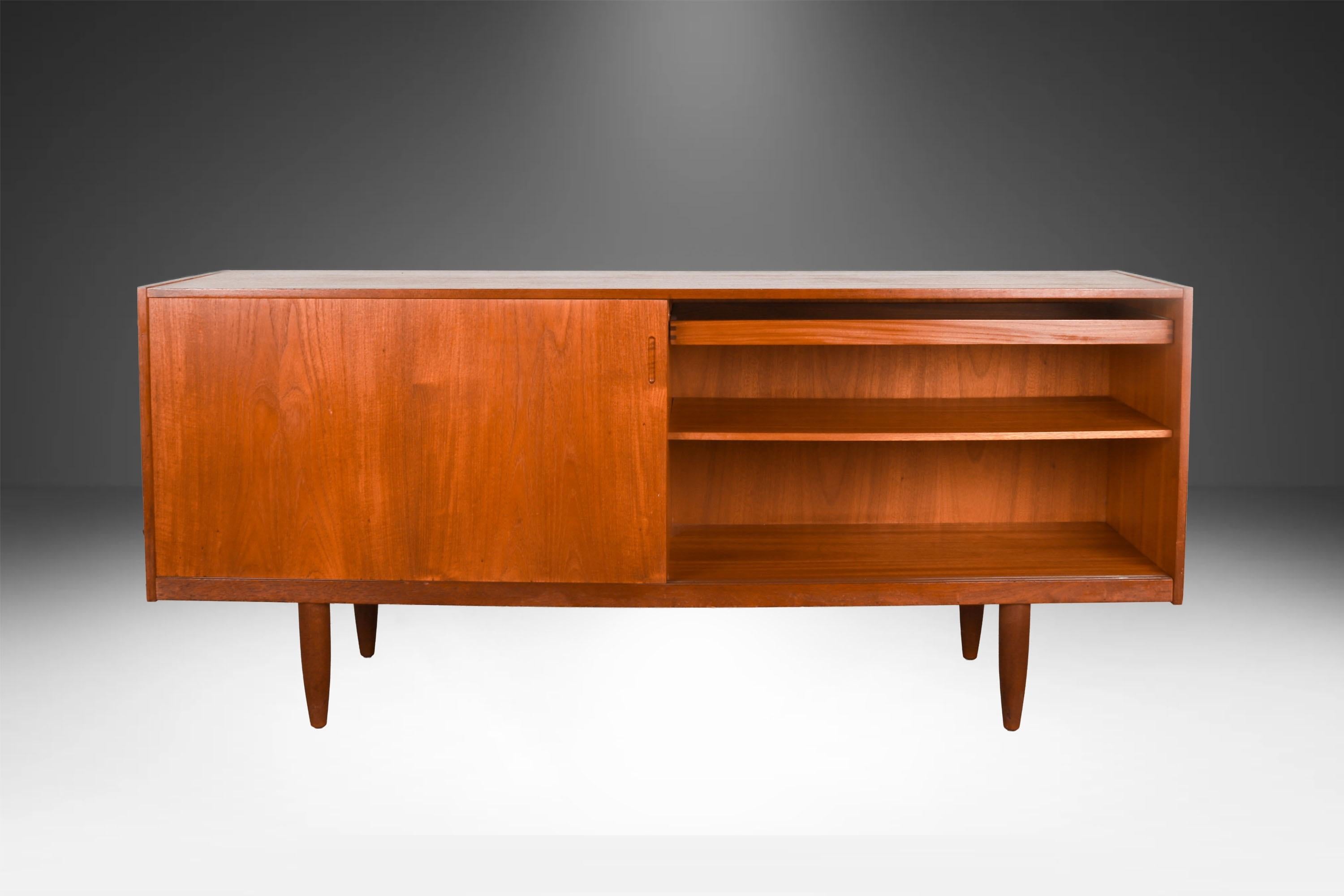 Bemerkenswerte Schiebetür-Credenza aus Teakholz, hergestellt in Dänemark. Diese dänische moderne Teakholz-Credenza ist wunderschön mit senkrecht zur Hauptfläche verlaufenden Teakholzstreifen verziert. Präzise in außergewöhnlicher warmer