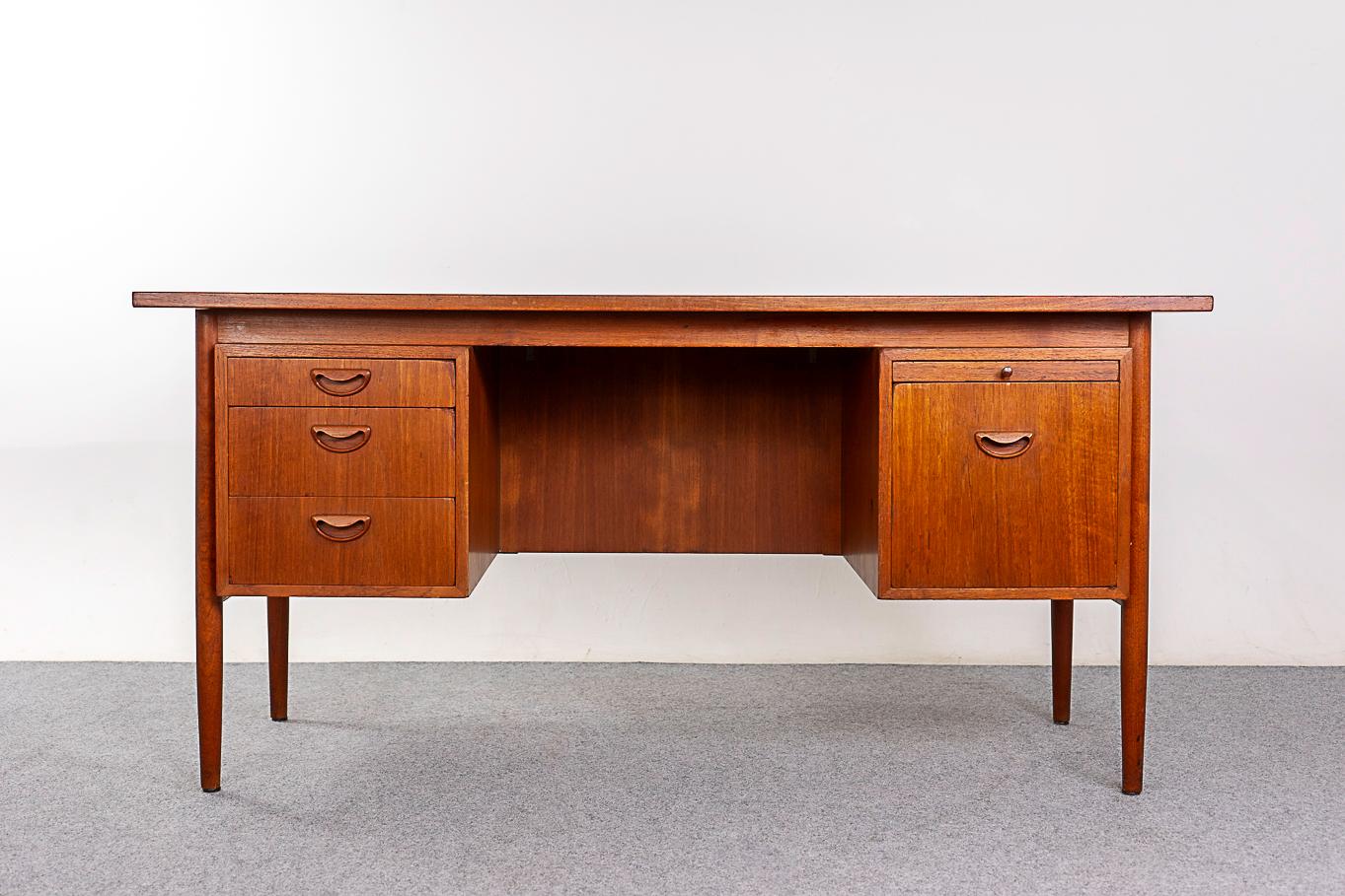 Teak Danish desk by Hundevad, circa 1960's. Finished on both sides, this desk can be placed in the center of a room and look fantastic from every angle! Lovely finger pulls, fitted interior, ample space for your office needs. Danish Furniture