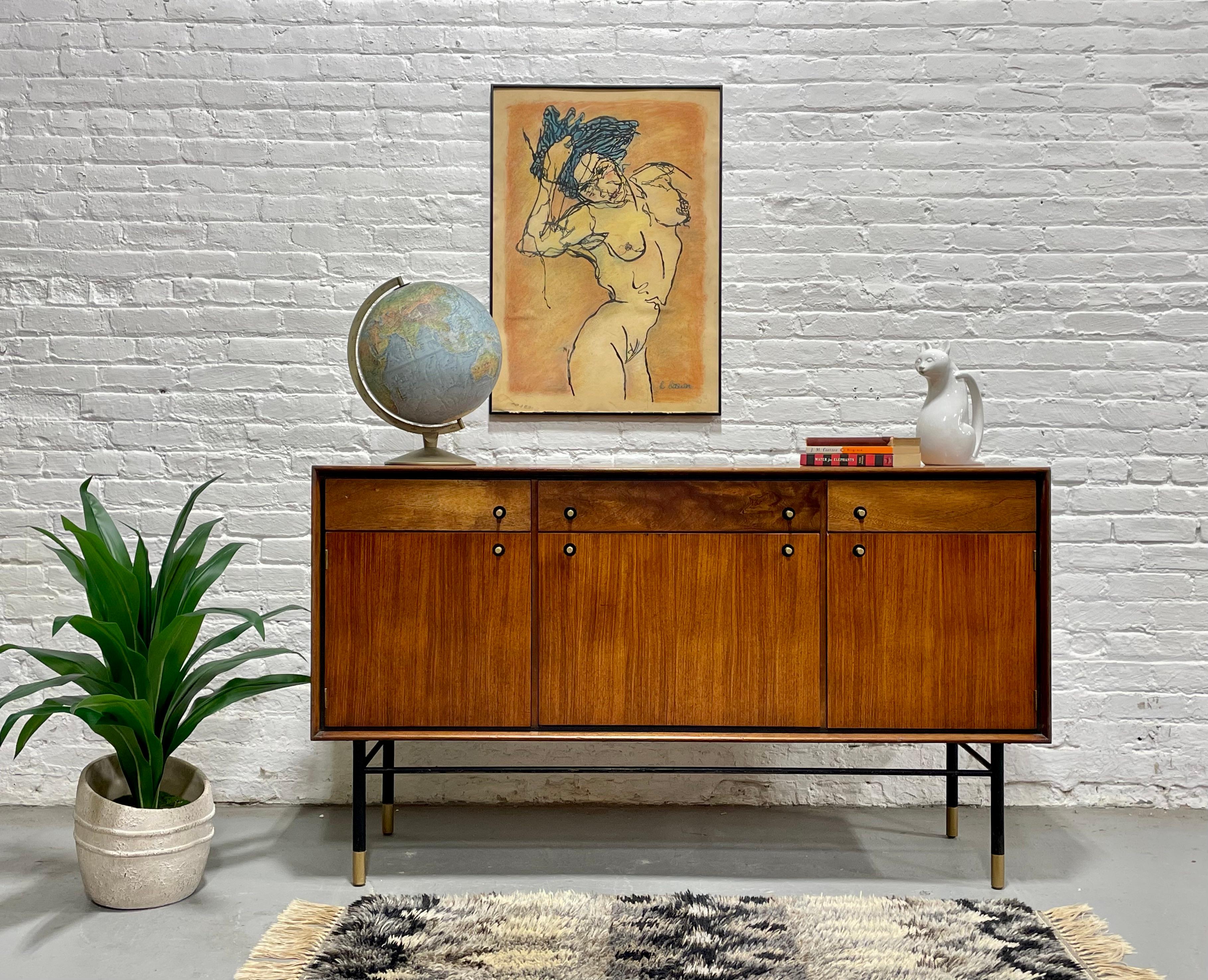 Credenza de teca moderna de mediados de siglo, Made in Denmark, c. 1960's. Este magnífico aparador es realmente único en su especie, con preciosas vetas de madera y una base ebonizada con patas rematadas en latón que complementan los tiradores de
