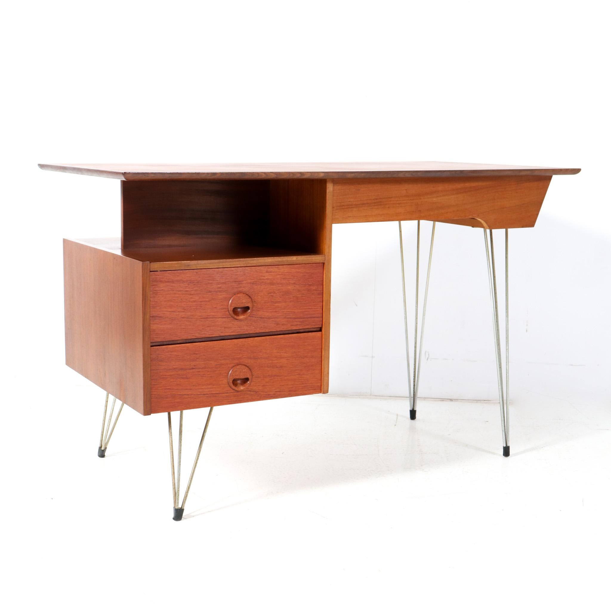 Stunning and elegant Mid-Century Modern desk or writing table.
Design by Louis Van Teeffelen for WéBé.
Striking Dutch design from the 1950s.
Minimalistic design in solid teak and original teak veneer with original lacquered metal hairpin legs.
Two