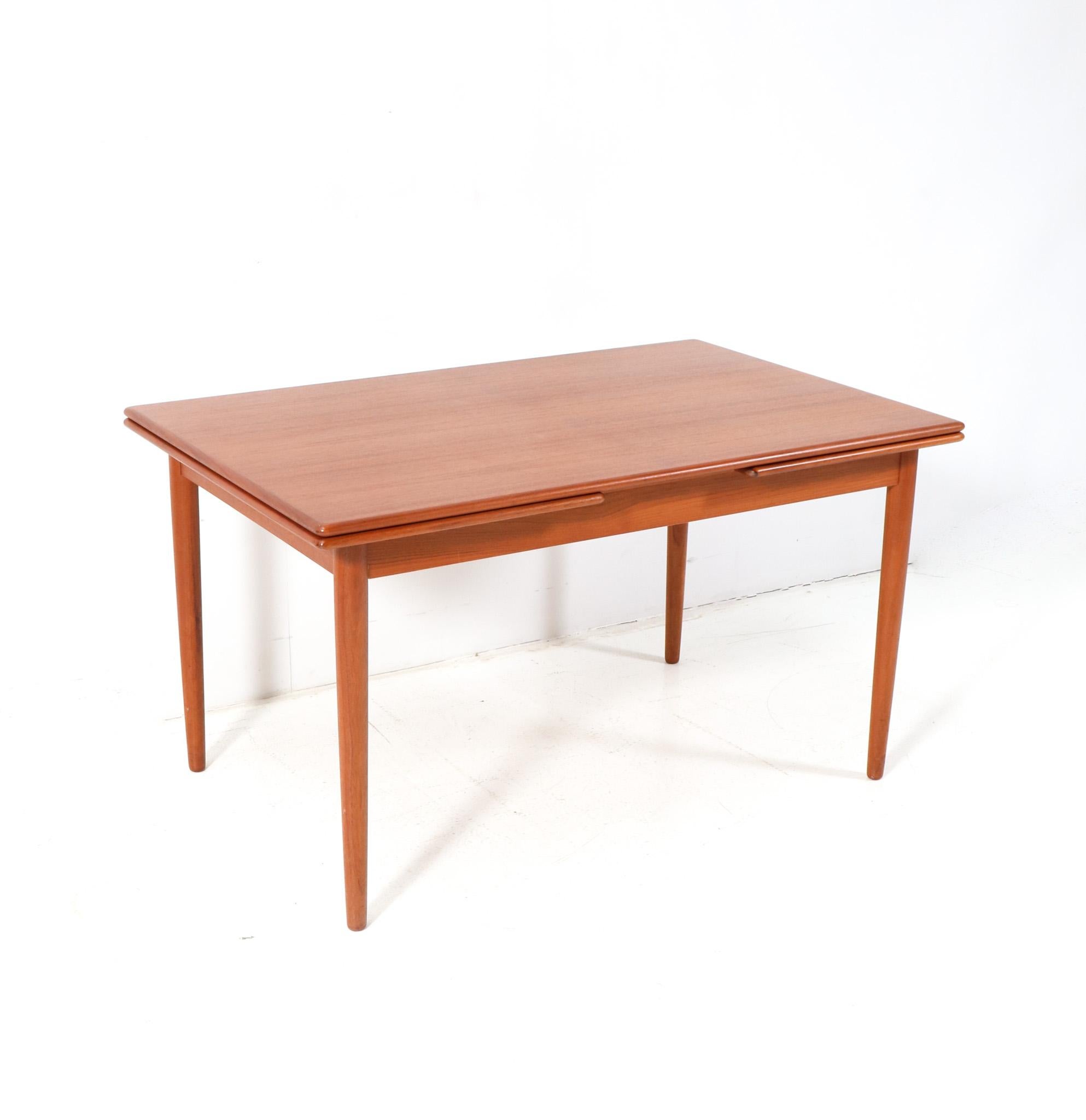 Stunning and rare Mid-Century Modern Mo. 215 extendable dining room table.
Design by Farstrup Denmark.
Striking Danish design from the 1960s.
Solid teak round tapered legs with original teak veneered top and two original teak veneered