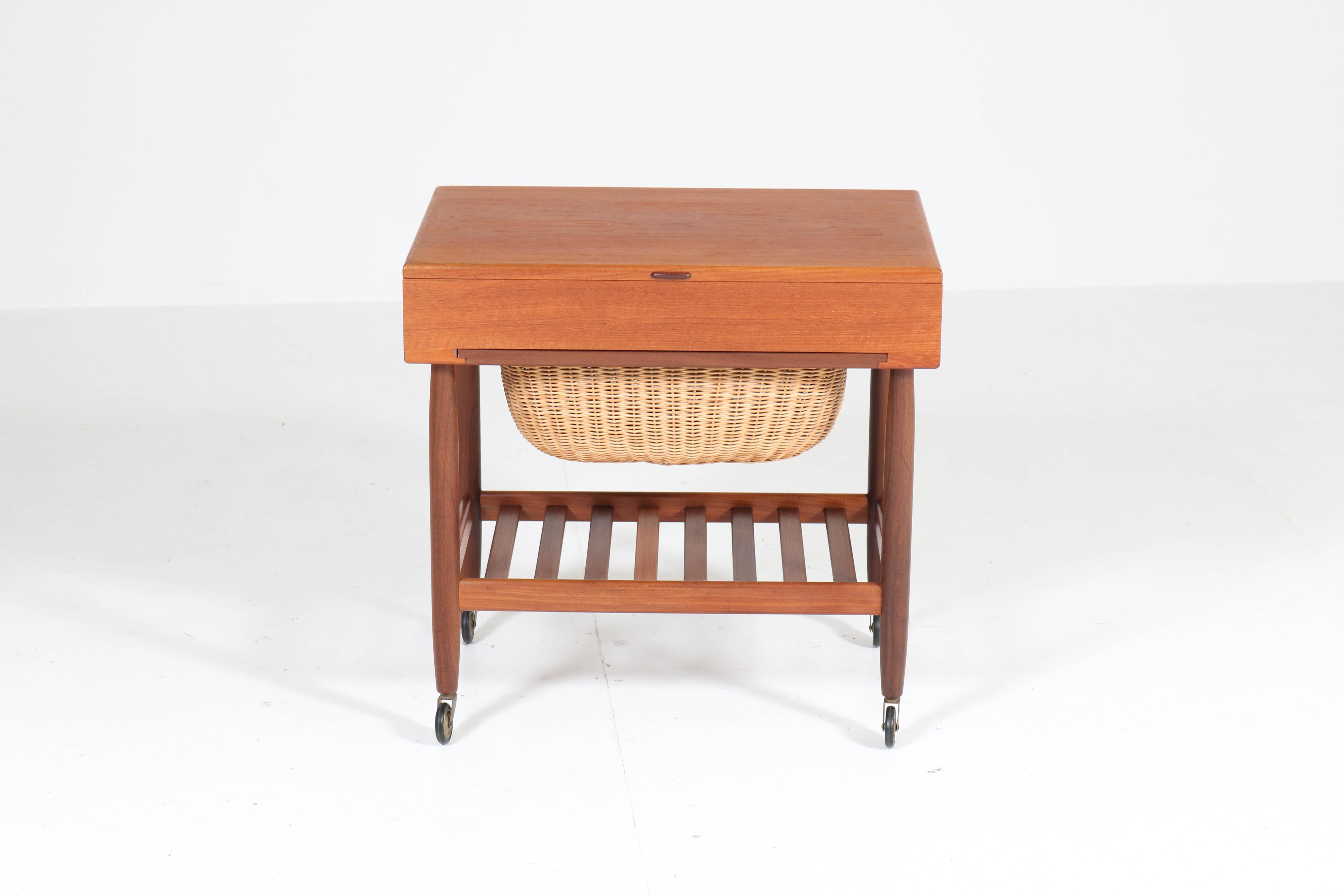 Stunning Mid-Century Modern sewing trolley.
Design by Ejvind Johansson for FDB Mobler.
Striking Danish design from the sixties.
Solid teak with original wicker basket.
Marked: made in Denmark,see image 12.
In very good original condition with minor