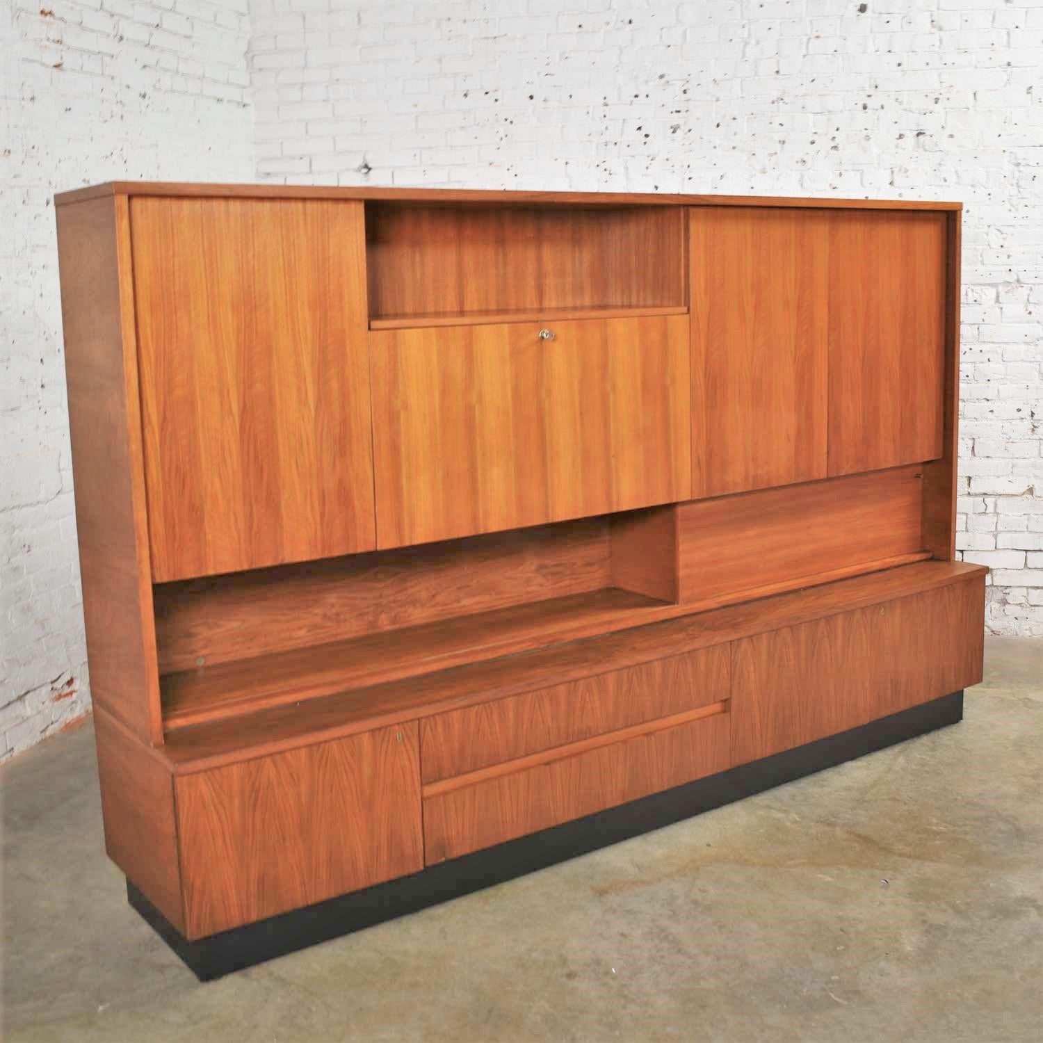 Handsome Mid-Century Modern or Scandinavian Modern large wall storage cabinet and bookcase with a drop front desk in teak. It is in wonderful vintage condition but not without some signs of age appropriate wear. Please see photos, circa mid-20th to