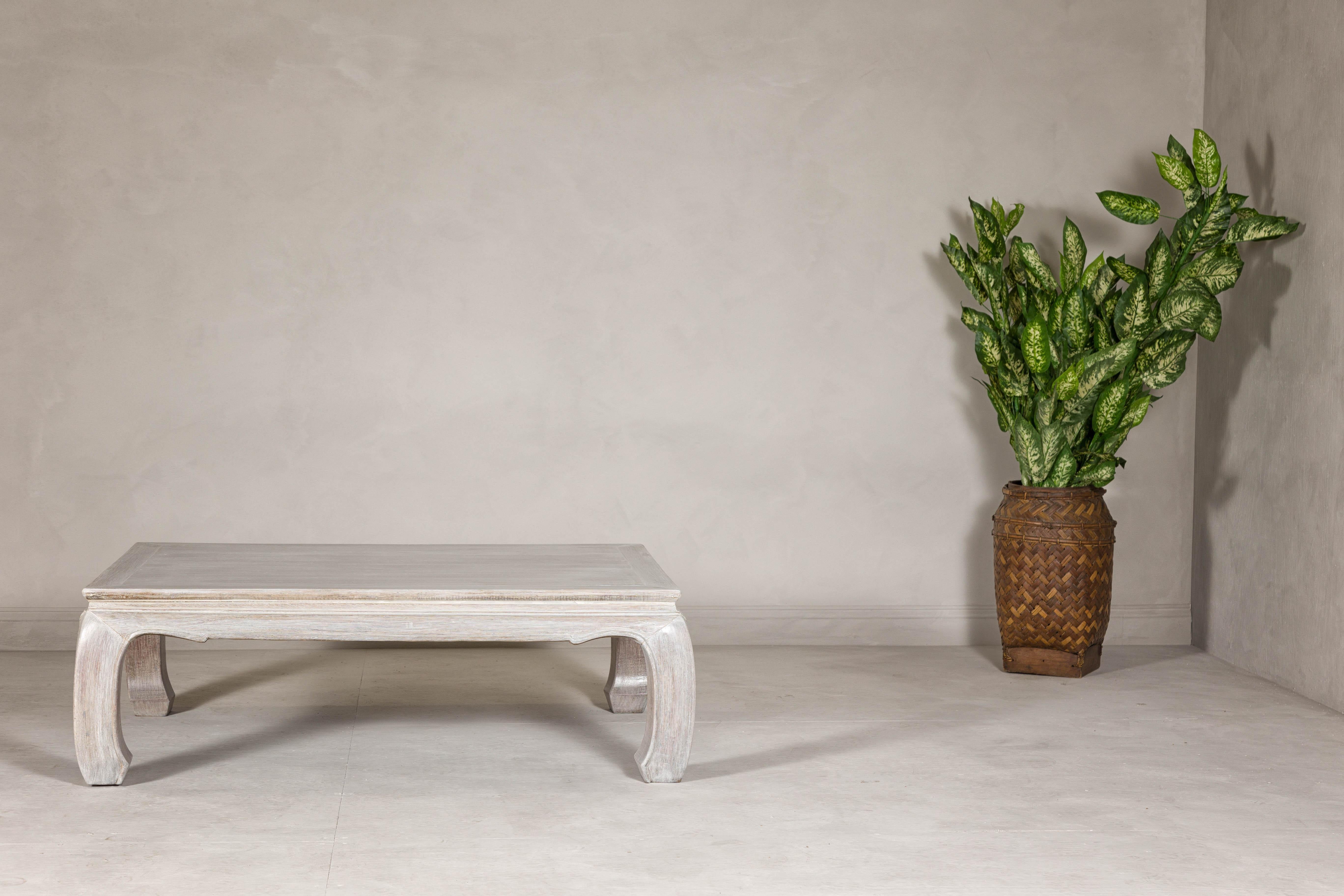 A teak wood Ming style whitewash coffee table from the 20th century with chow legs and weathered patina. This vintage teak wood coffee table, styled in the Ming tradition and finished with a whitewash, breathes a serene, timeless elegance into any