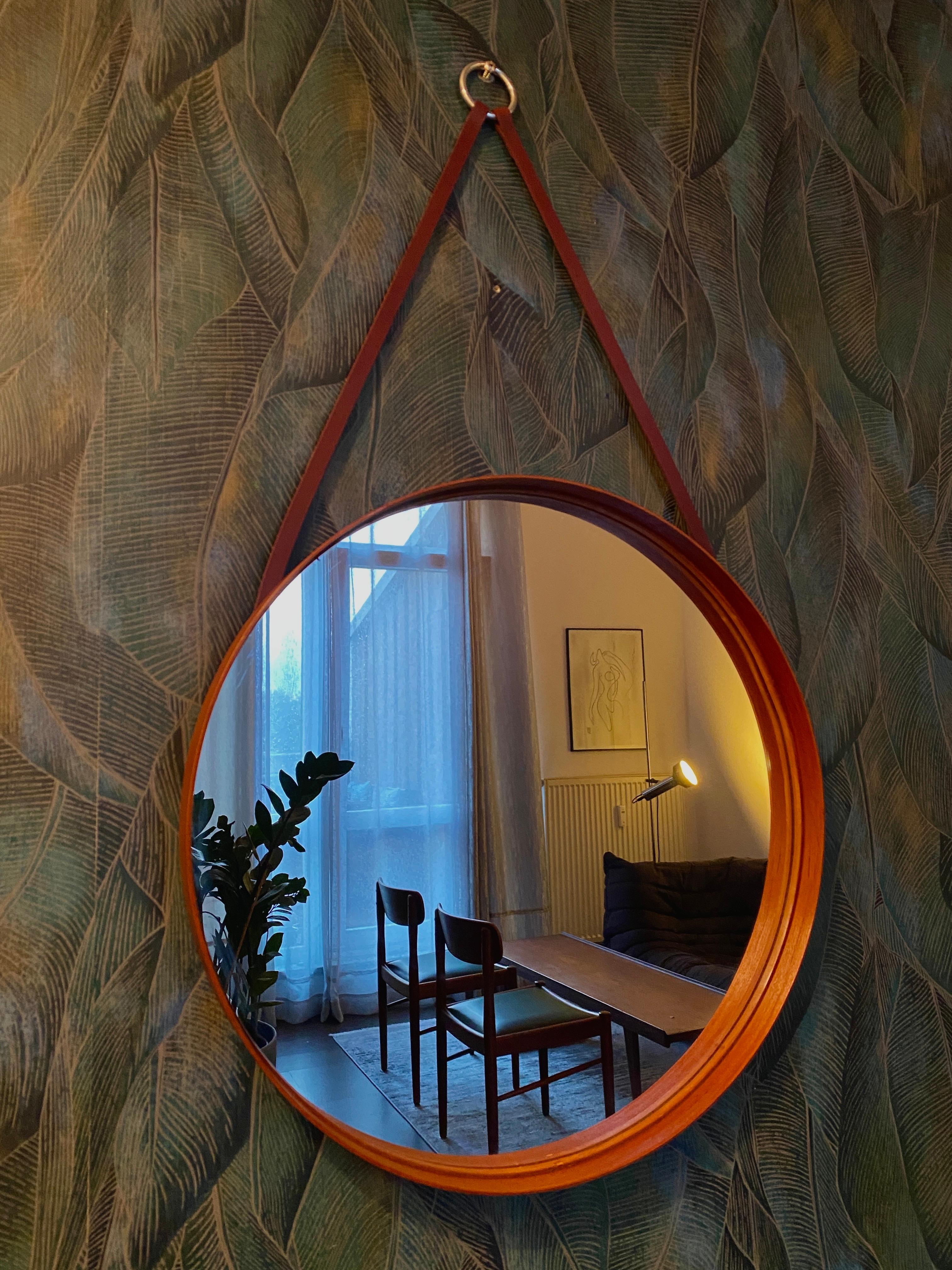 Miroir en verre rond avec un cadre en teck fin et simple.
Il est muni d'un anneau en métal et d'une lanière en cuir. Une étroite lanière de cuir est collée à l'intérieur pour maintenir le miroir en place.
Vers les années 1950

Dimensions :
Hauteur