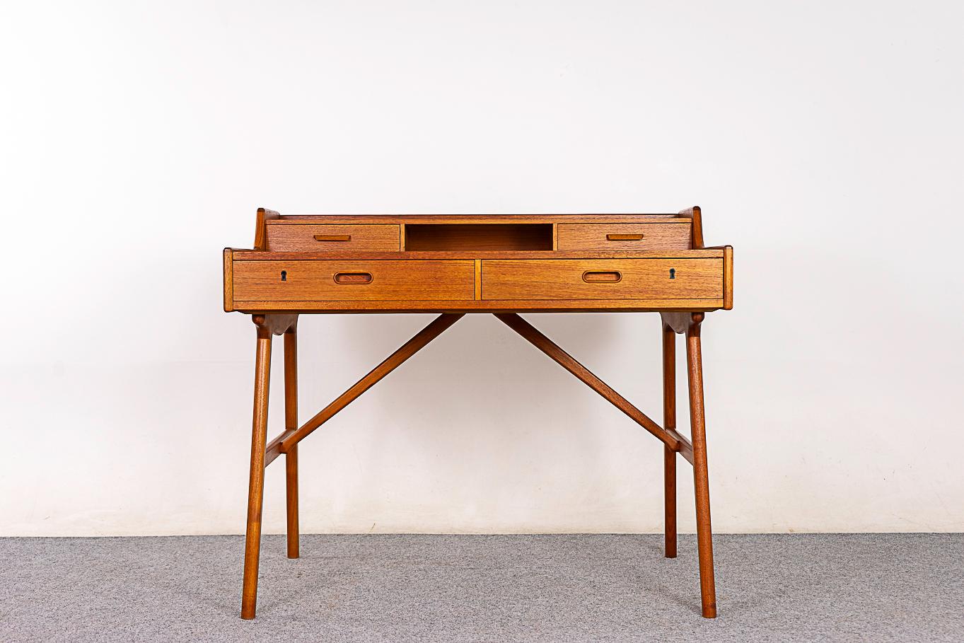 Teak Danish Model 64 desk by Arne Wahl Iversen, circa 1960's. Stunning two tiered desktop with beautiful bookmatched veneer. Elegant, sculptural solid teak base with diagonal cross braces. Deep lower locking drawers and sleek uppers. Beautiful
