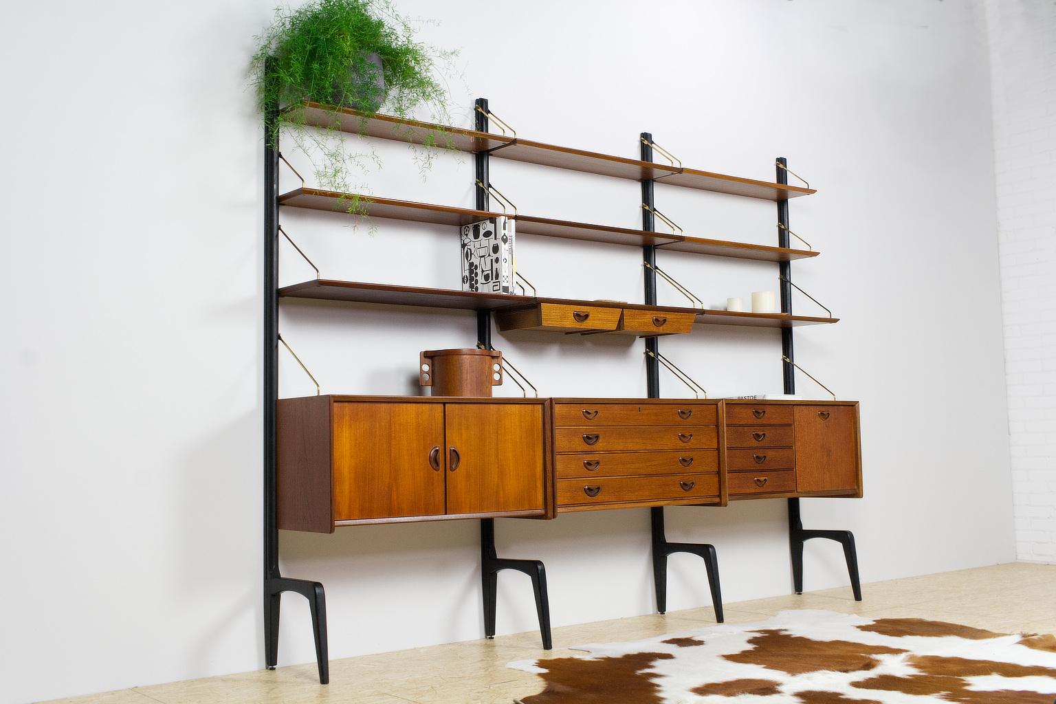 Well detailed 1950s teak wooden wall unit by Dutch designer Louis Van Teeffelen. The modular unit can stand alone and contains 3 cabinets, 1 drawer/shelf unit, 8 shelves and 4 black wooden uprights. The teak wooden, high quality, veneered elements