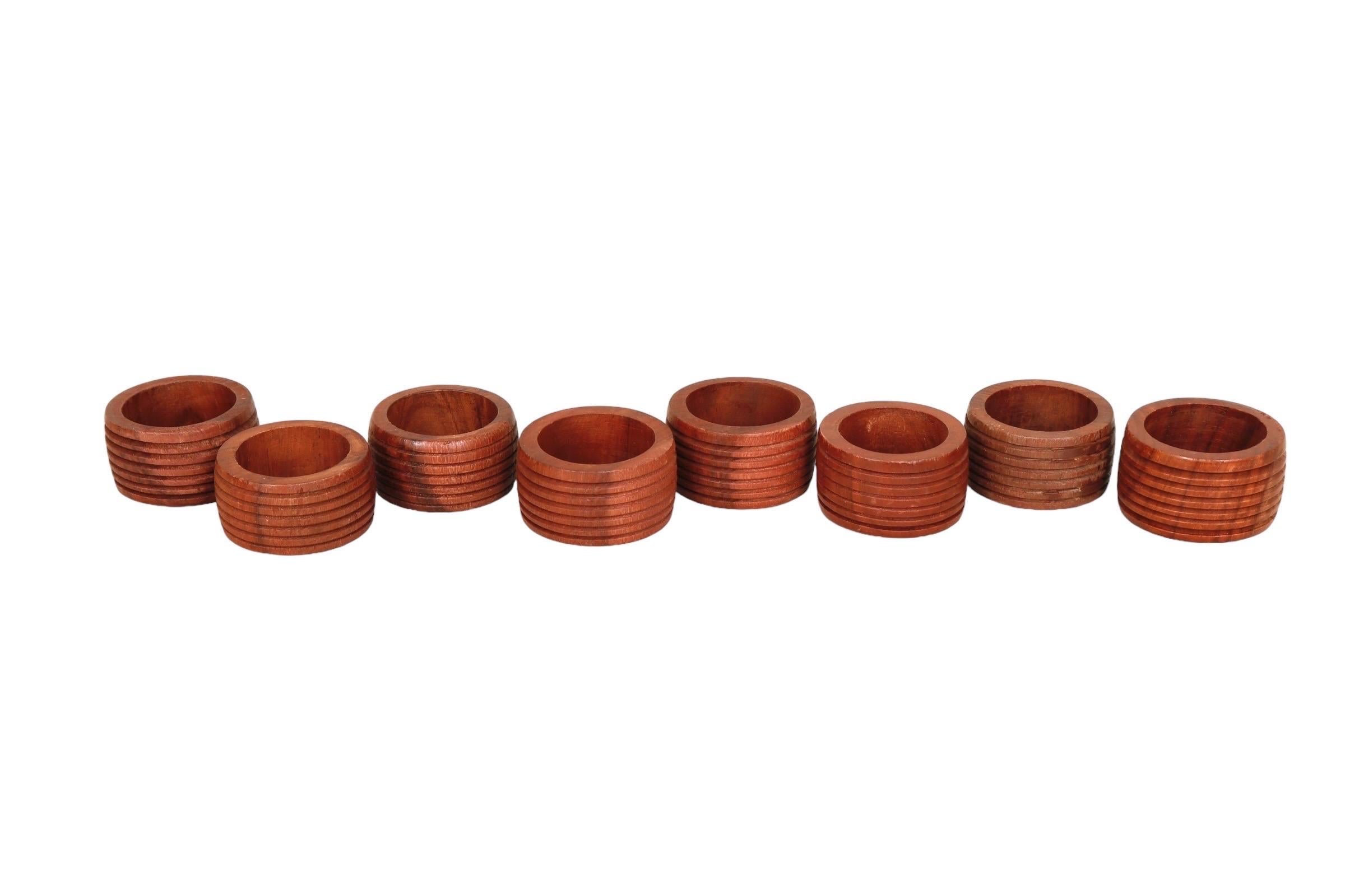 A set of eight napkin rings, made of teak. Richly grained wood is carved in a gentle barrel shape, finished with six fluted lines. Dimensions per napkin ring.
