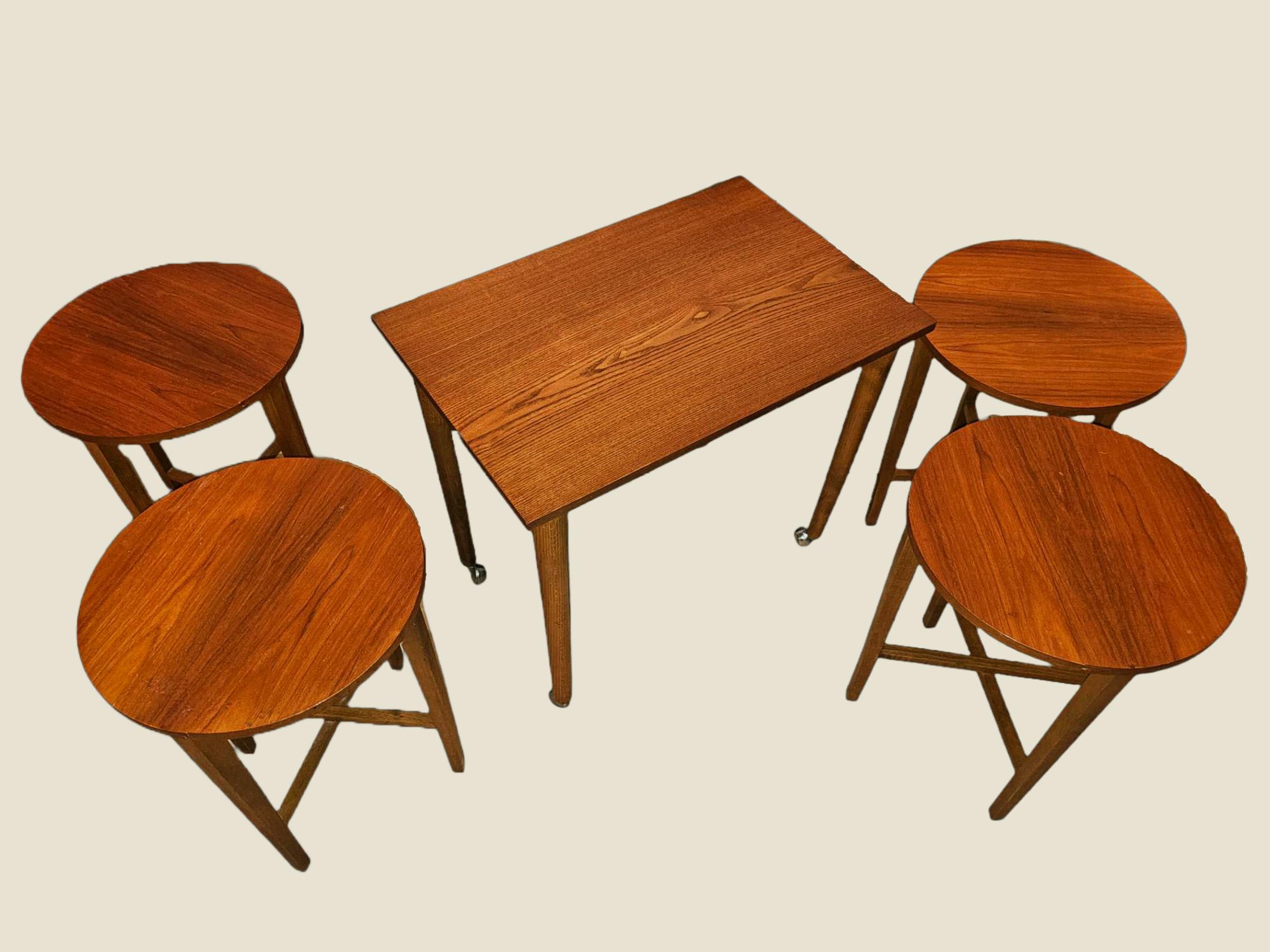Dieses einzigartige Set wurde von Poul Hundevad für Novy Domov entworfen und stammt aus den späten 1960er Jahren. Der größte Tisch ist rechteckig und mit Rädern ausgestattet und beherbergt 4 klappbare runde Tische, von denen jeder zusammengeklappt