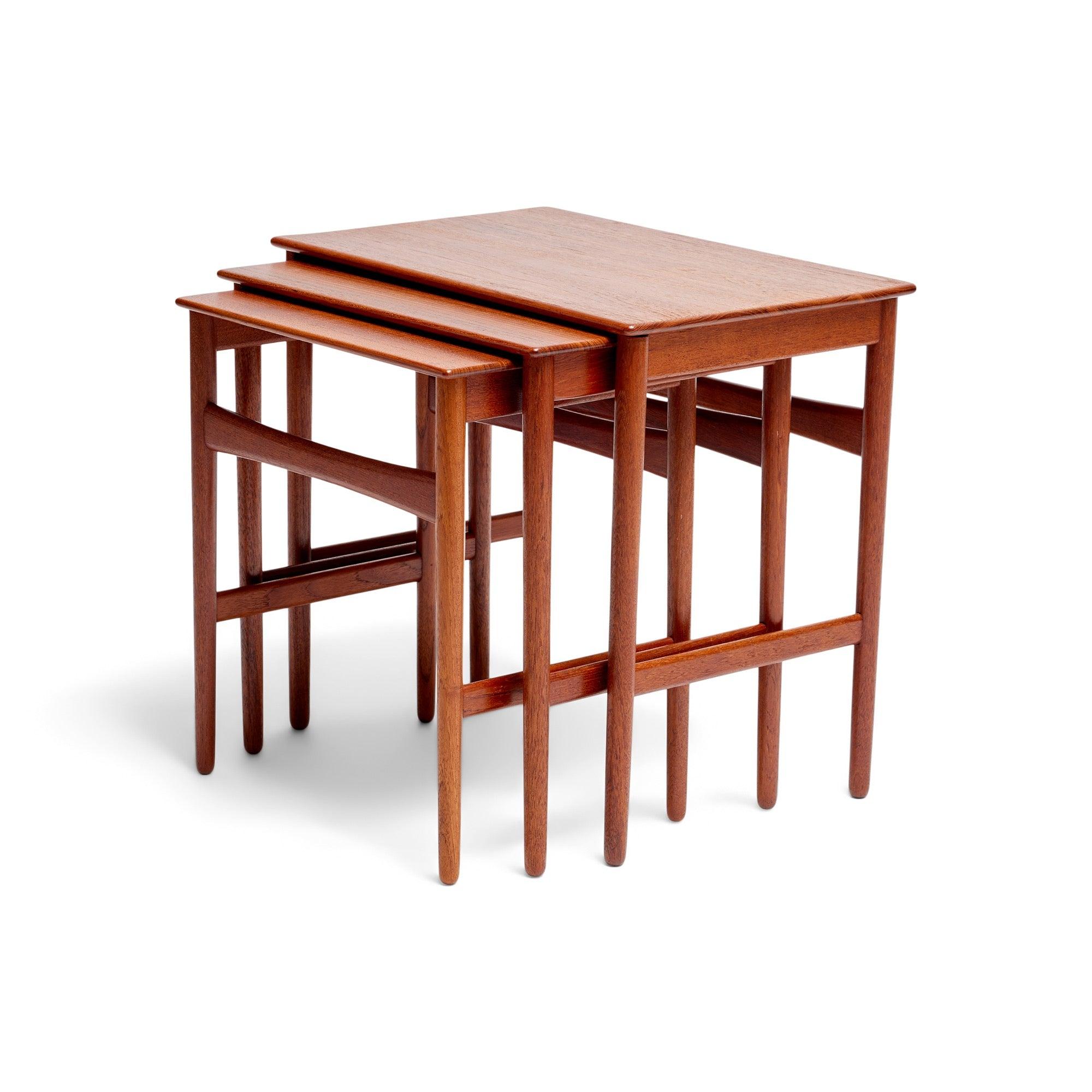 A set of three teak nesting tables with overhanging tops and tapered dowel legs.