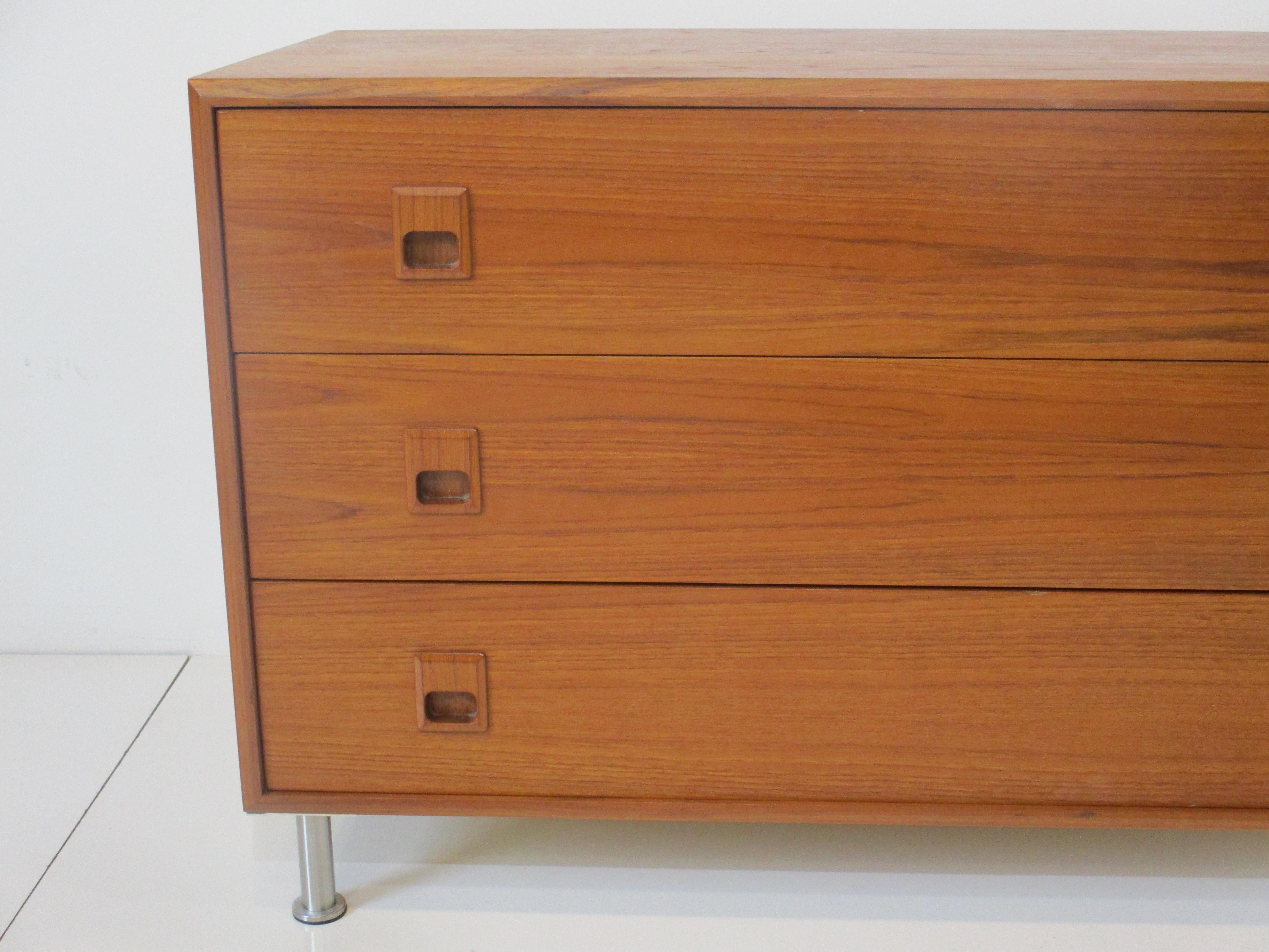 A very well made smaller scaled three drawer teak chest or nightstand with squared pulls to the face . Sitting on adjustable brushed stainless steel legs with protective foot pads for your floors manufactured in Canada in the manner of Arne Vodder .