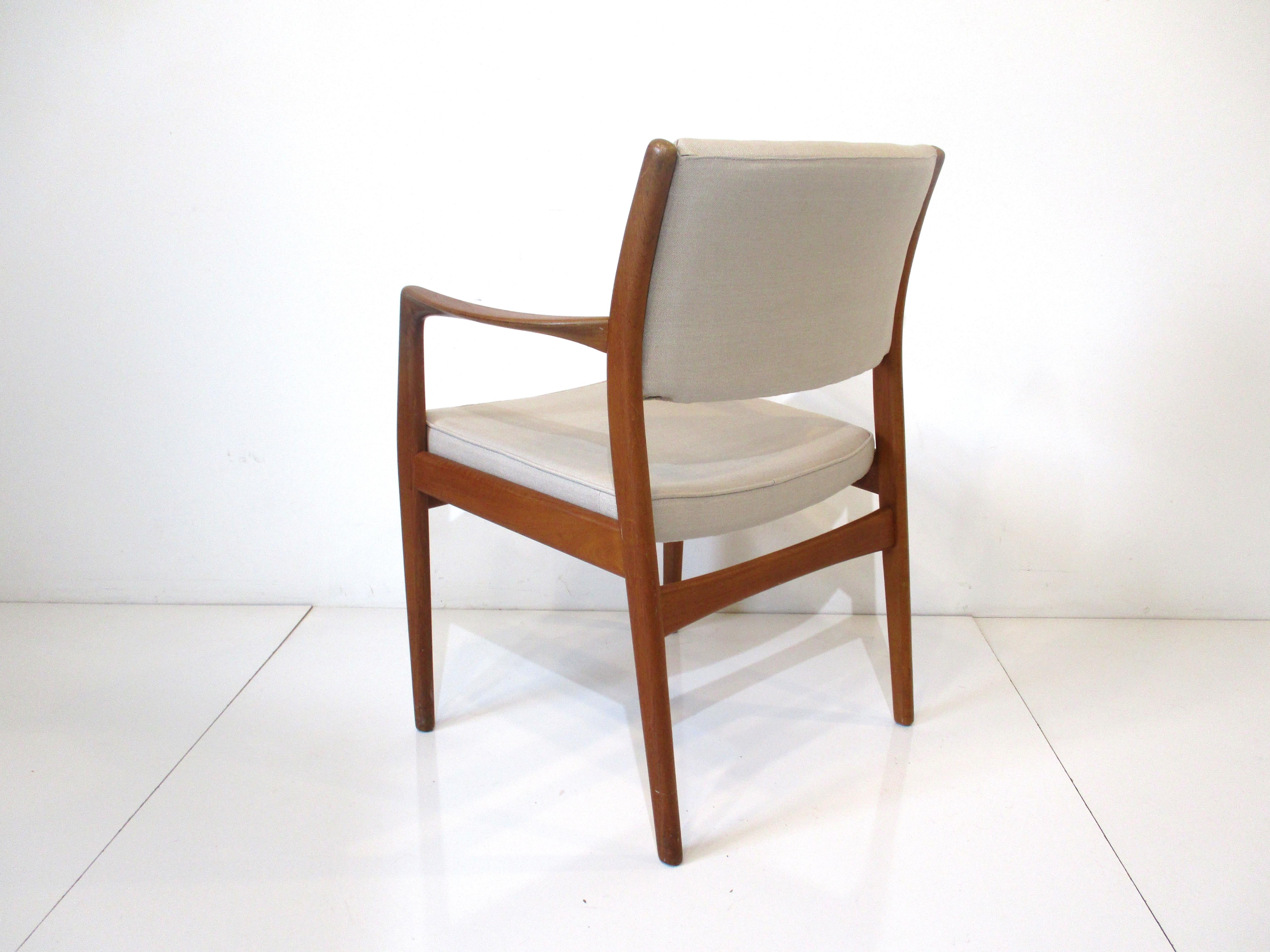 A solid teak framed occasional chair with flared arms and upholstered in a cream toned tightly woven linen. Retains the manufactures branded mark to the seat bottom by Dux made in Sweden, a nice comfortable chair for your sitting area.