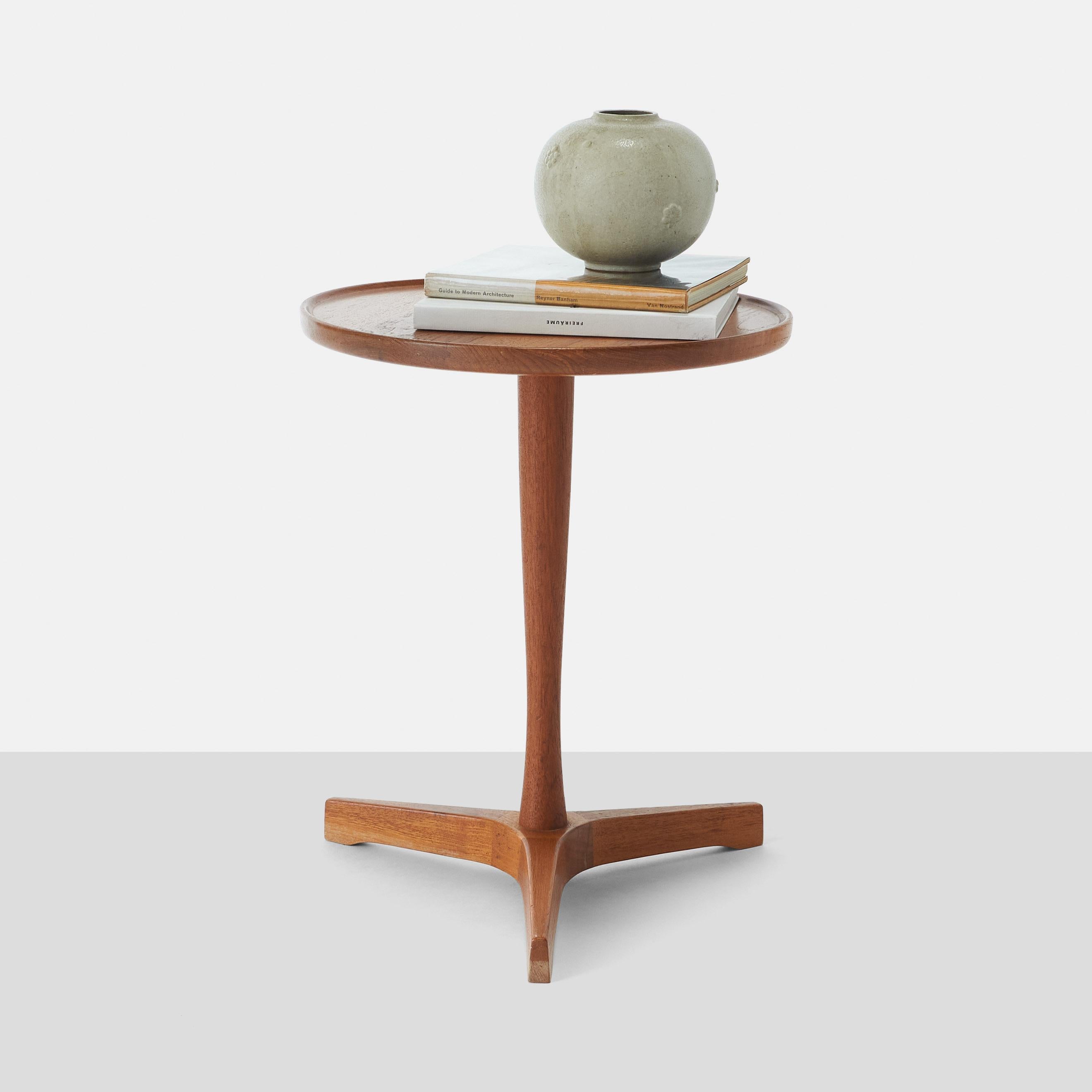 A vintage Scandinavian Modern round side table in teakwood with a veneered top and tripod base. With maker's mark 