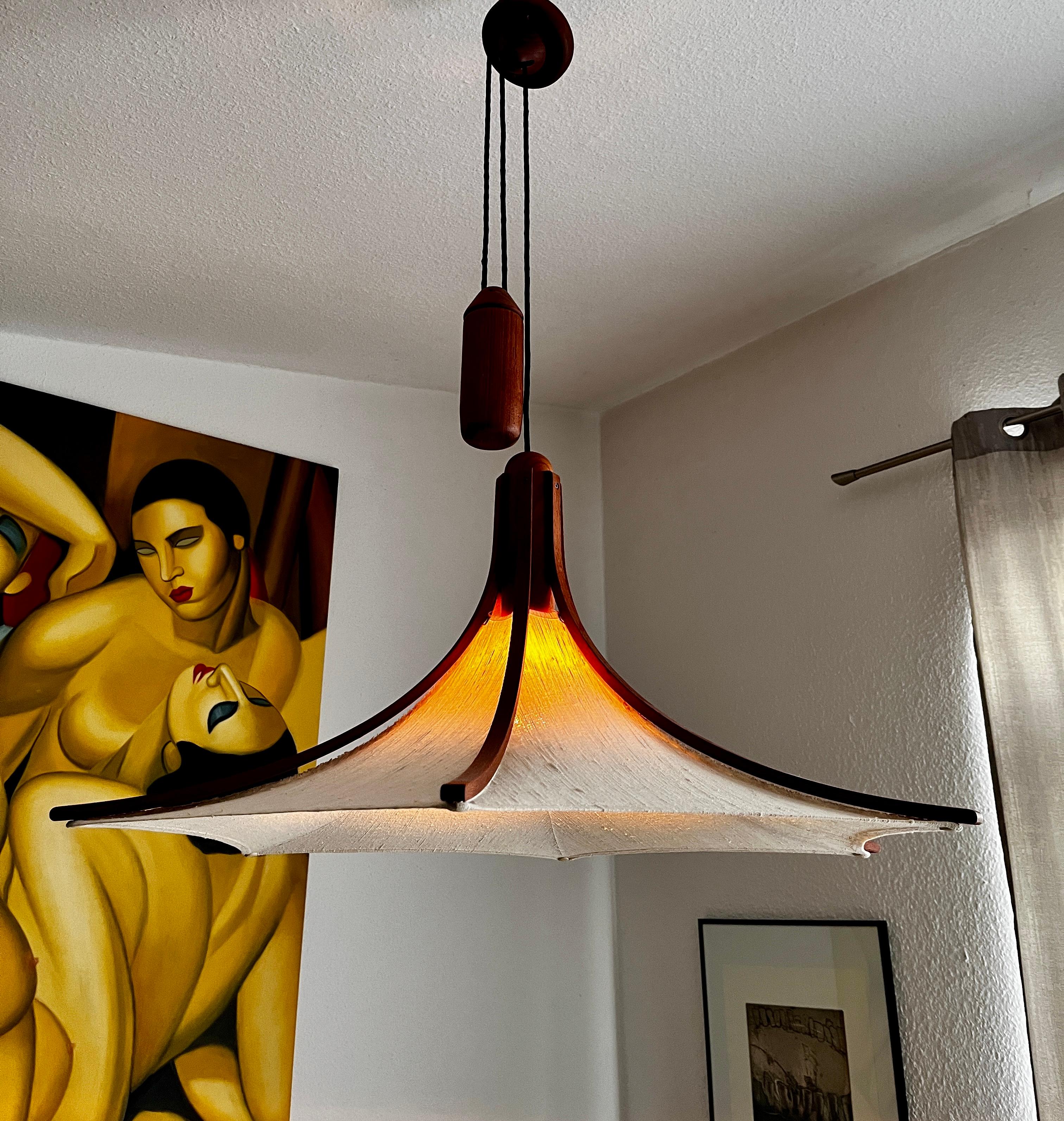 Gran lámpara colgante extensible de teca, de Domus, años 60.
La longitud de la lámpara se puede ajustar mediante el mecanismo de tracción. El mecanismo de tracción (peso del péndulo) funciona, y la longitud de la cuerda se puede ajustar tirando de