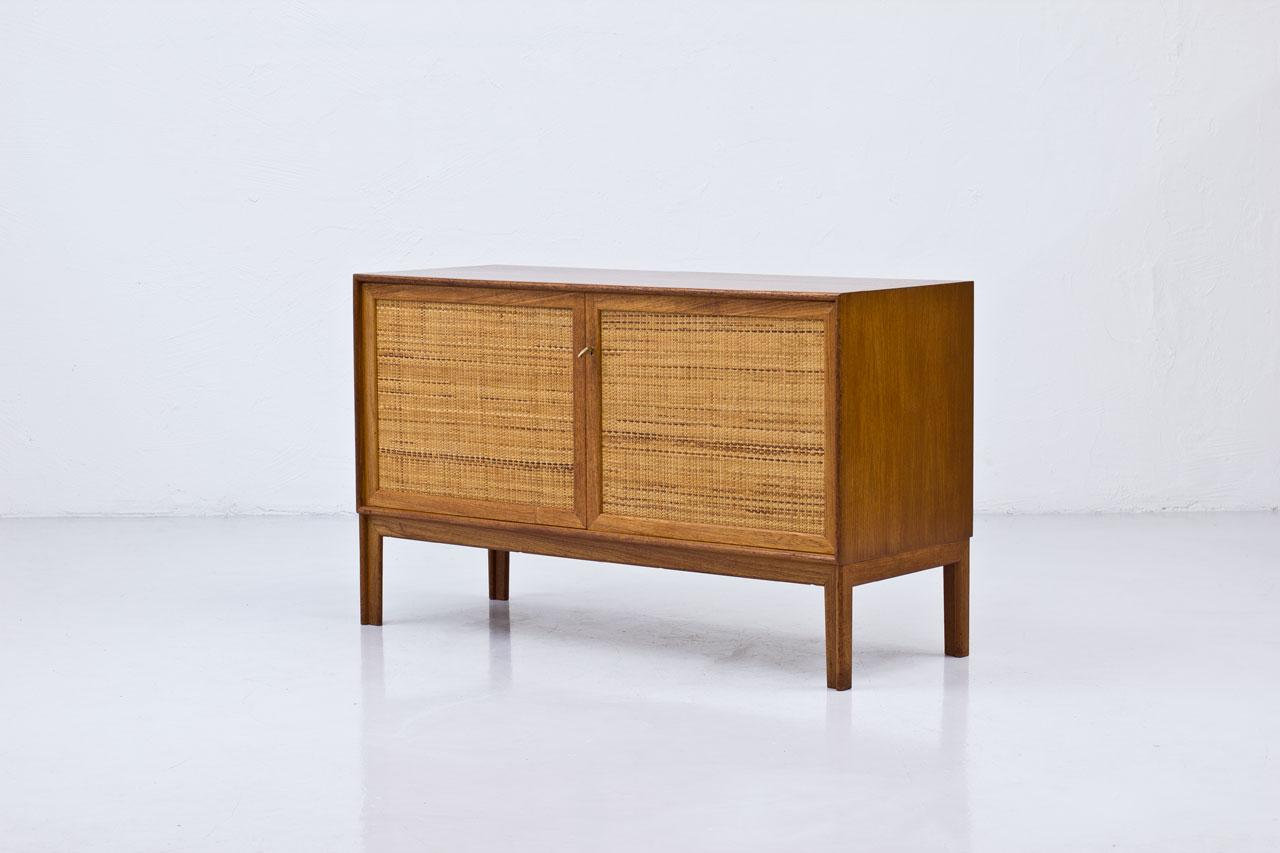 Sideboard designed by Alf Svensson
manufactured by Bjästa Möbelfabrik in
Sweden during the 1960s. Made from
teak with two doors panel covered by
rattan webbing. Brass key. Inside in
birch with shelves and drawers. Signed
by maker.