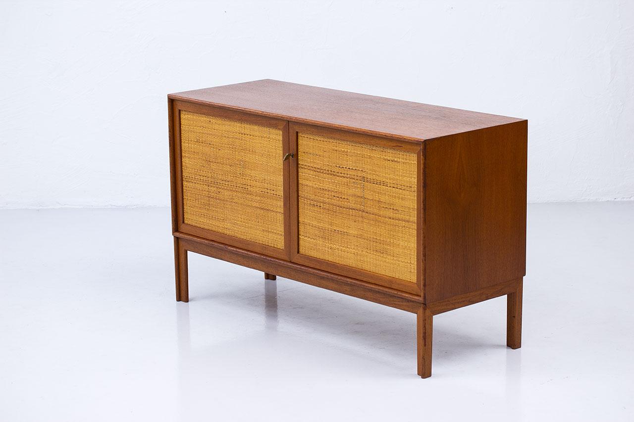 Elegant and neat sideboard designed by Alf Svensson, manufactured by Bjästa Möbelfabrik in Sweden during the 1960s (design circa 1950s). Made from teak with two doors panel covered by rattan webbing. Beautiful brass key. The inside is in birch with
