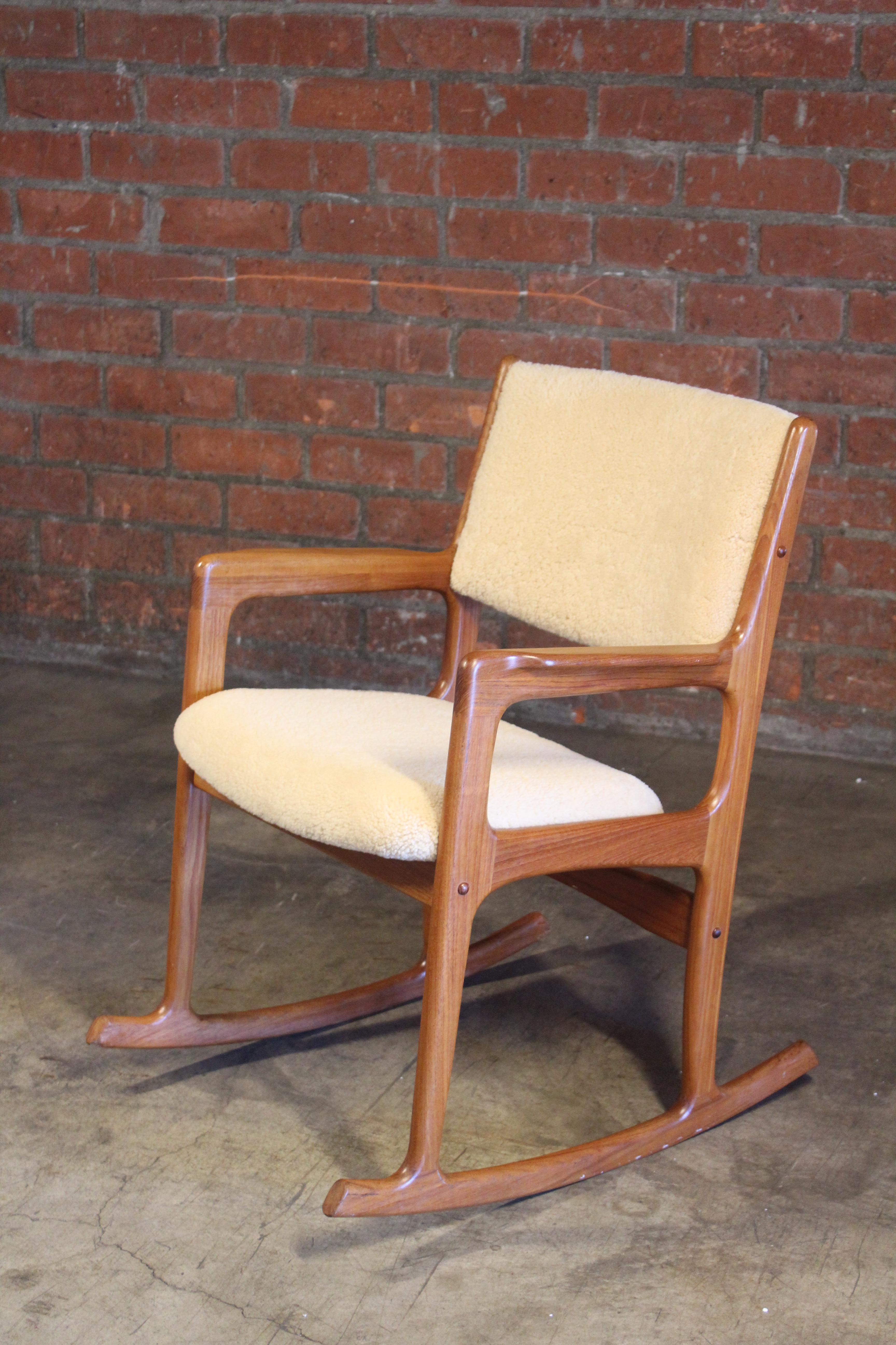 A vintage 1960s teak rocking chair from Denmark, newly upholstered in sheepskin.