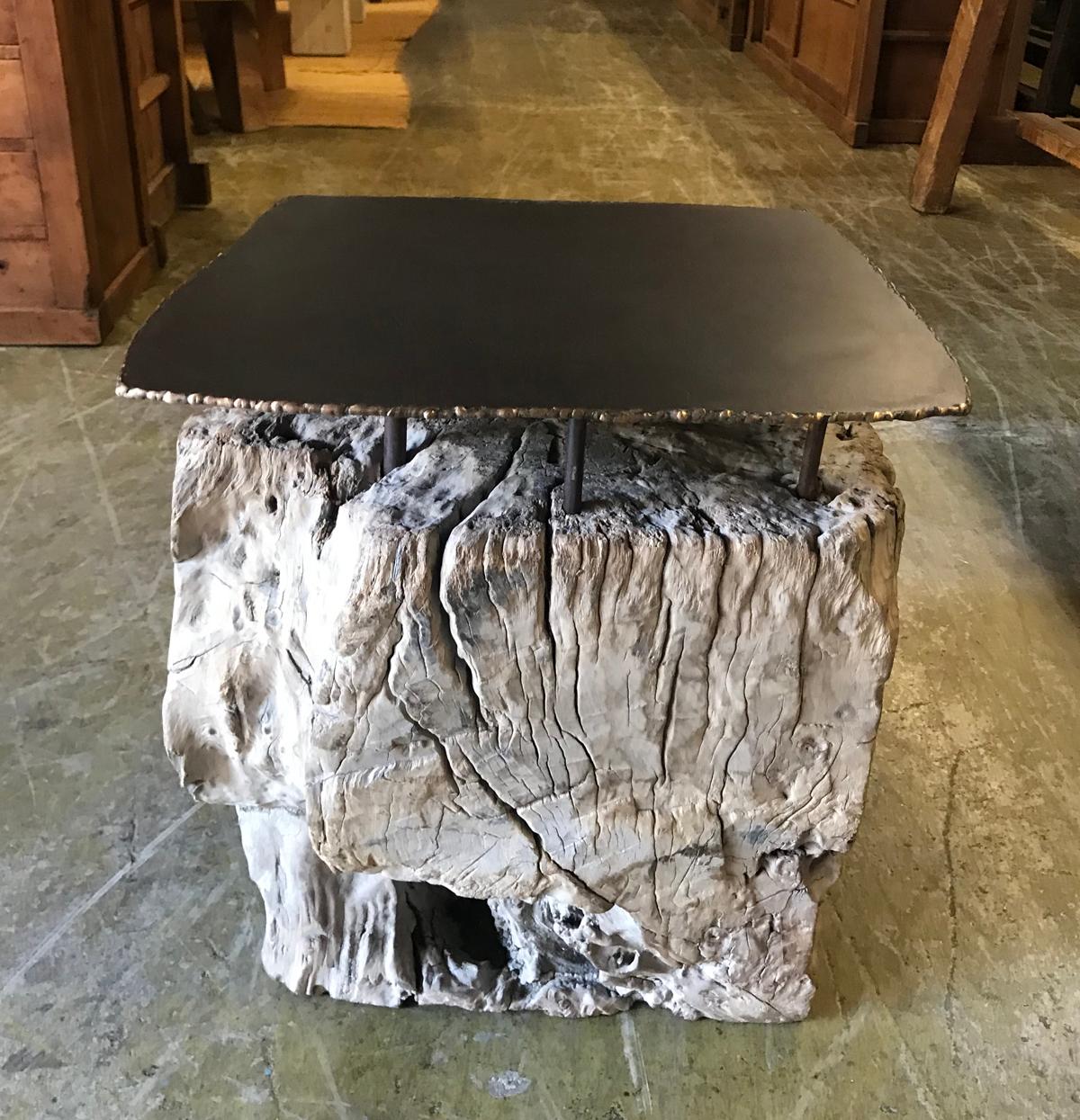 The juxtaposition of the weathered wood root  with an iron and bronze top makes this side table an unusual, unique, modern organic piece. The view of each side is different and interesting due to the natural crevices and undulation of the wood. The