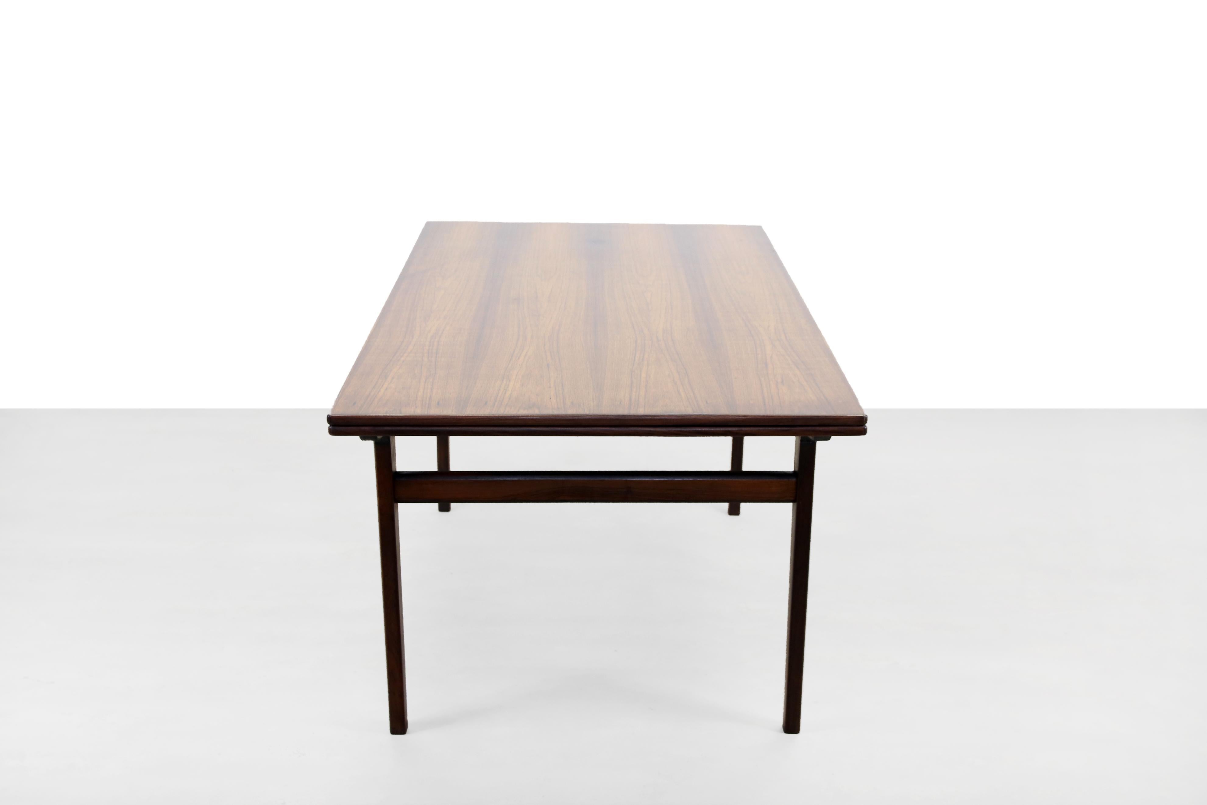 Beautiful large dark teak dining room table designed by the Dane Johannes Andersen. The table has two extra tops that are stylishly incorporated under the top and extendable so that 8-10 people can easily sit at the table. Solid Danish quality and a