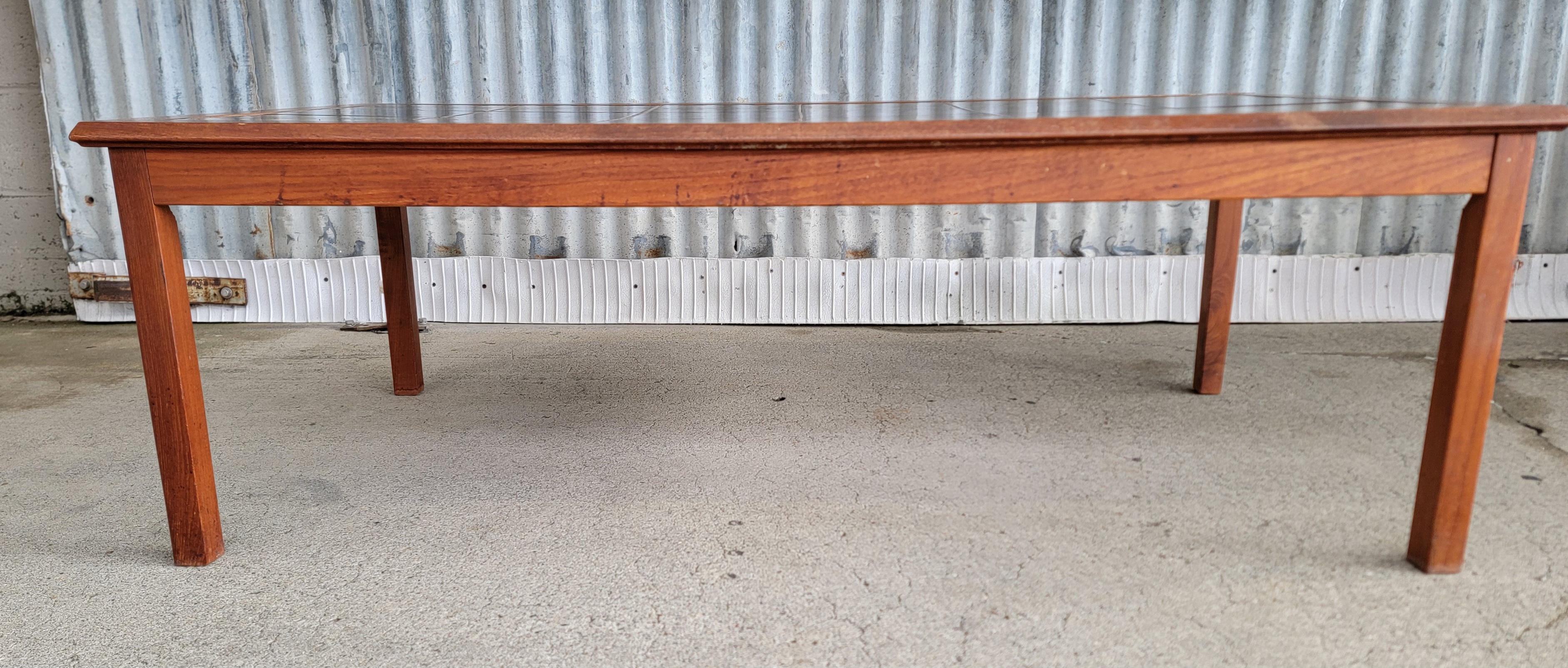 A teak and ceramic tile top Danish Modern coffee table. Made by Mobelfabrikken Toften, Norway. Circa. 1970. A set of 18 abstract gold and brown tiles in teak frame. Very good original finish and condition.