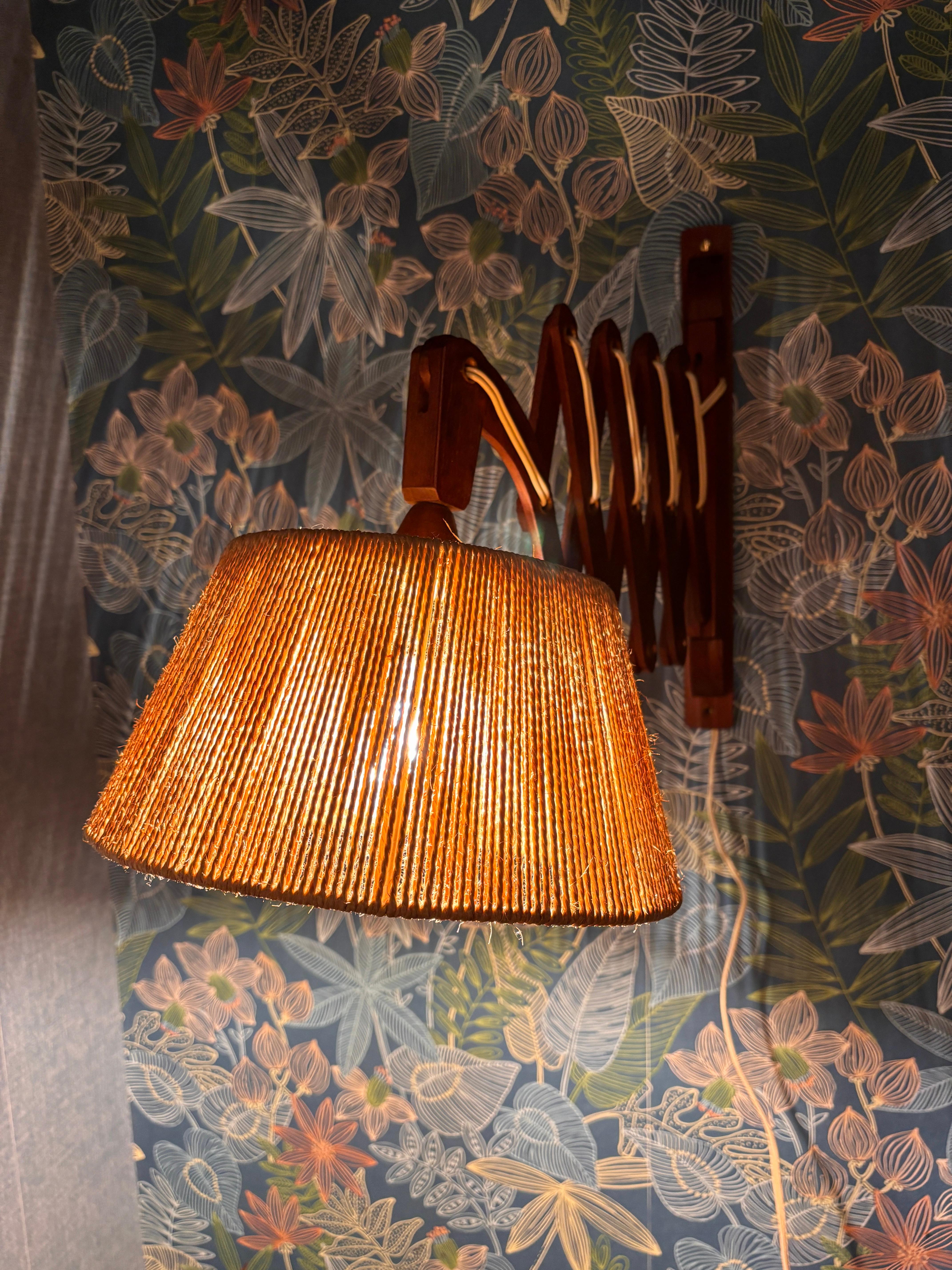 Teak wall lamp by Ib Fabiensen for Fog and Morup from the 1960s, made in Denmark. Featuring a teak scissor arm, the lamp radiates warmth and natural beauty. The original shade is made of hand-woven jute and the teak frame.

Diameter (shade): approx.