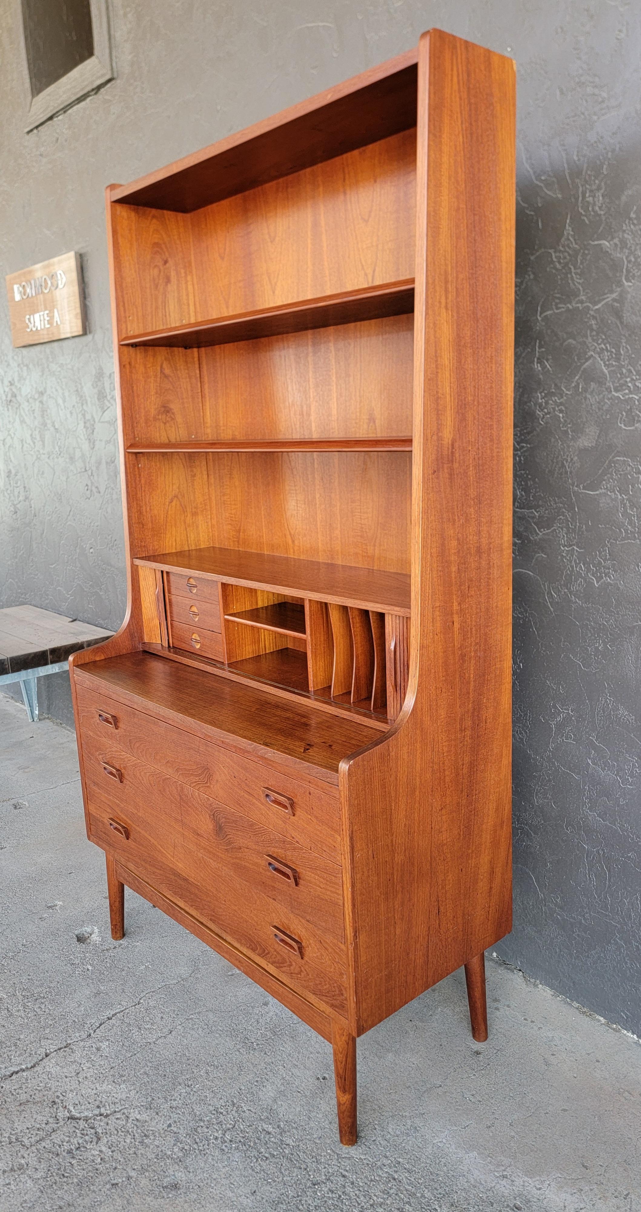 Scrivania danese moderna in teak con libreria disegnata da Johannes Sorth per Bornholm Mobelfabrik, Danimarca. Circa. 1960's. Le ante a tamburo si aprono su 3 piccoli cassetti e l'interno è dotato di buchi per piccioni. La superficie della scrivania