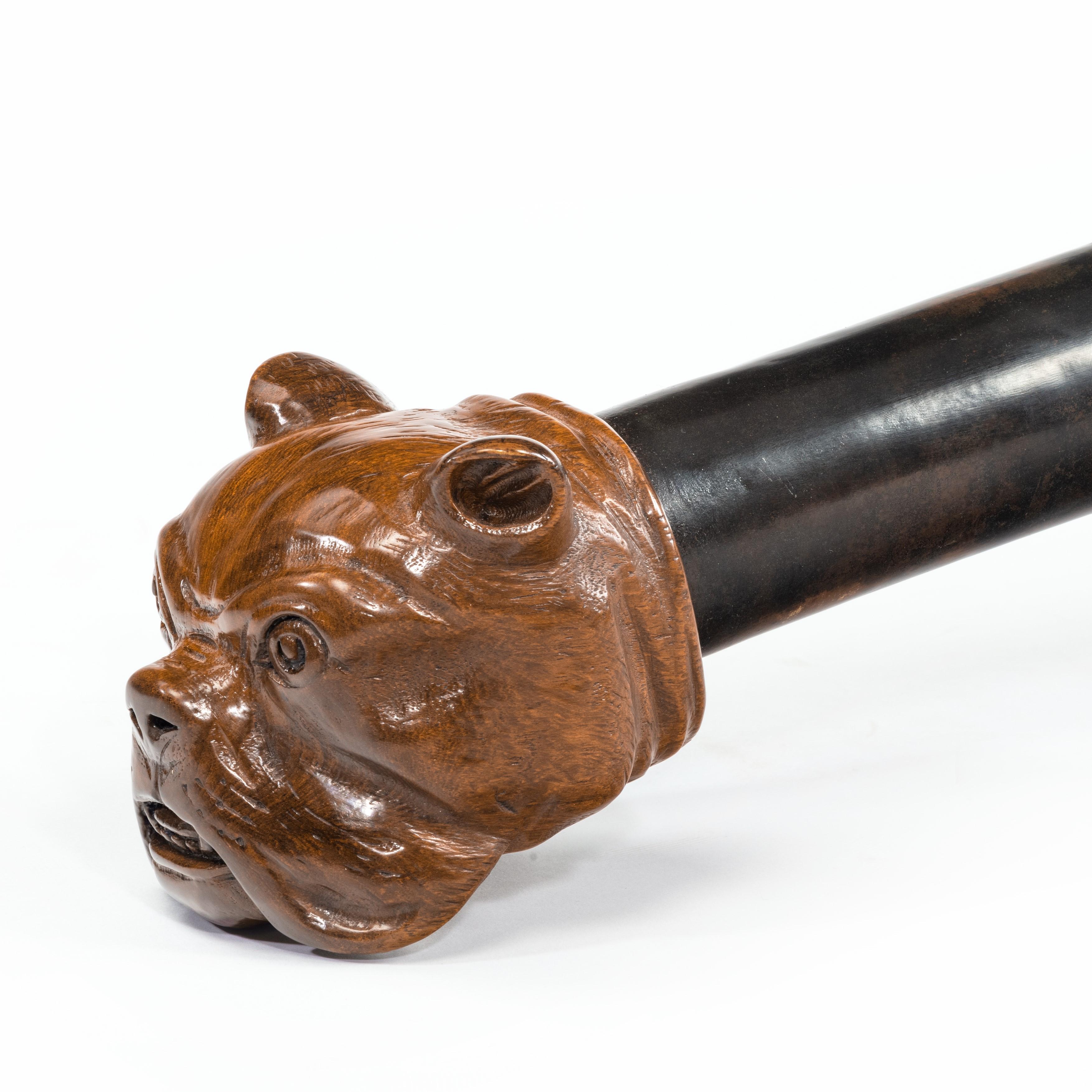 A teak ship’s tiller with a bulldog’s head, spirally carved and with old copper rivet repairs, English, circa 1900.
Measures: L 51 1/2in (131cm).
  
