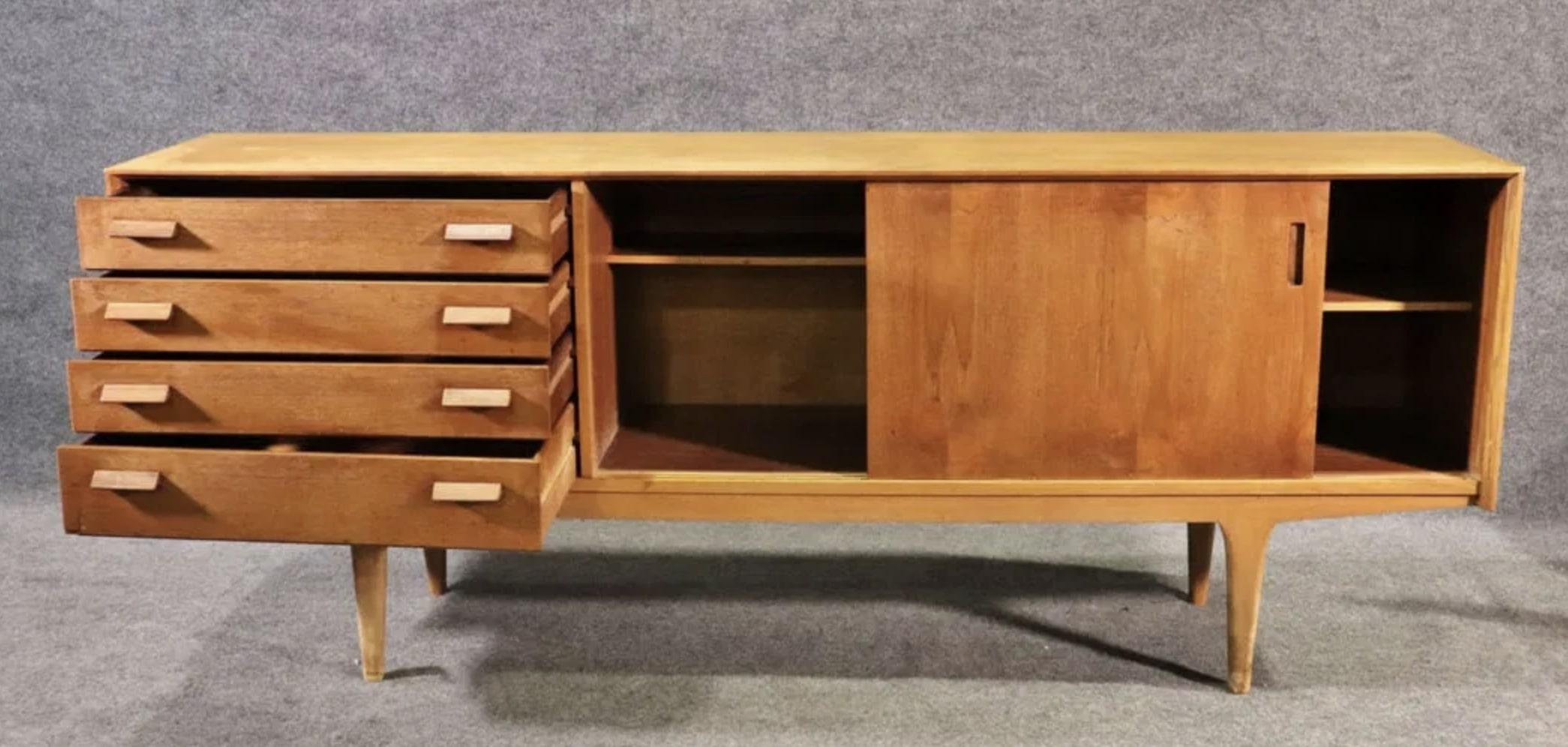 Bellissima credenza in teak realizzata da G-Plan nel Regno Unito. Quattro cassetti laterali e un armadietto ad ante scorrevoli per riporre gli oggetti. Le gambe affusolate e le maniglie in legno scolpito aggiungono un design accattivante.
Si prega