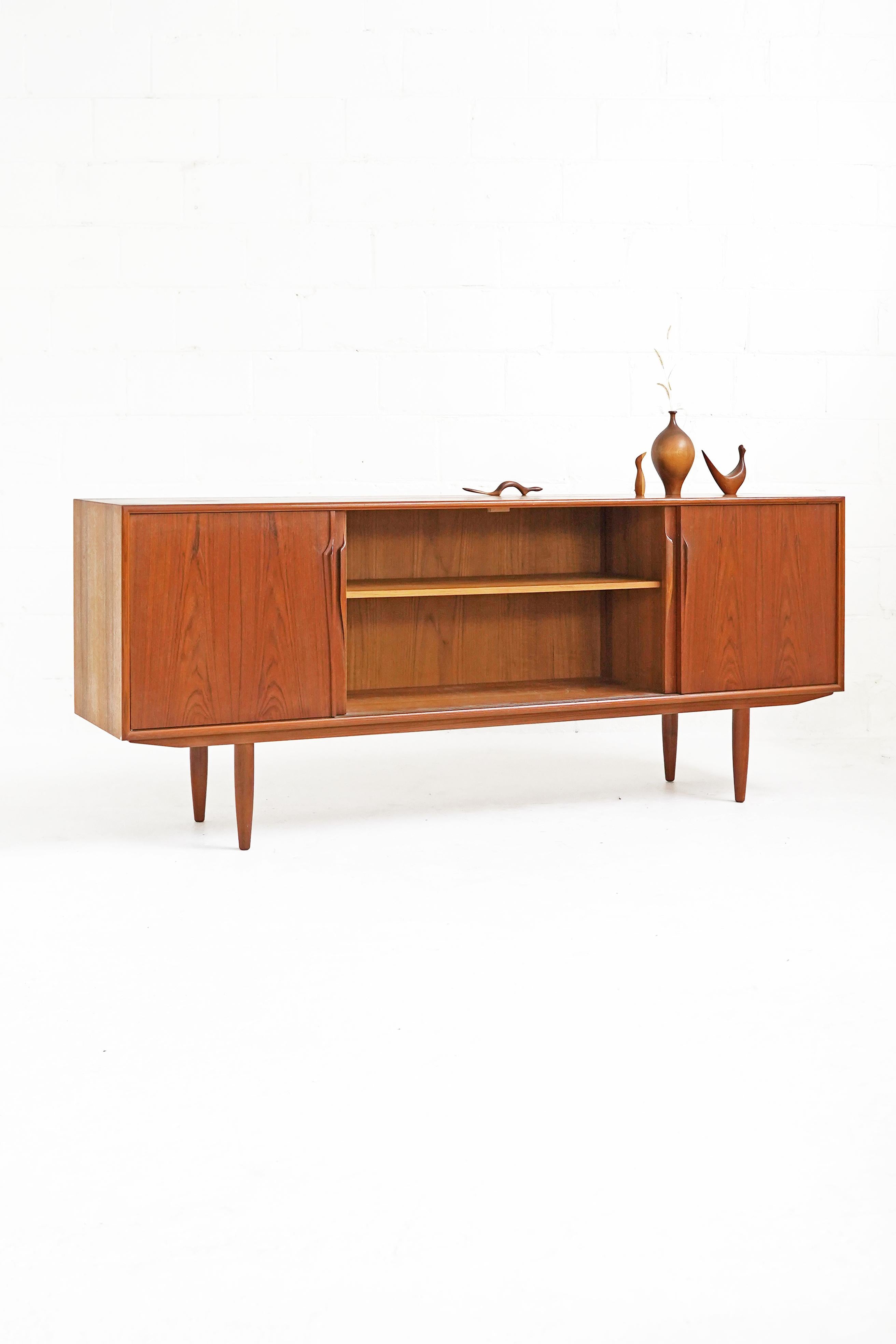 Stunning teak sideboard designed by Gunni Omann with beautiful bookmatched door fronts. In overall great vintage condition, has three inner drawers and two shelves.