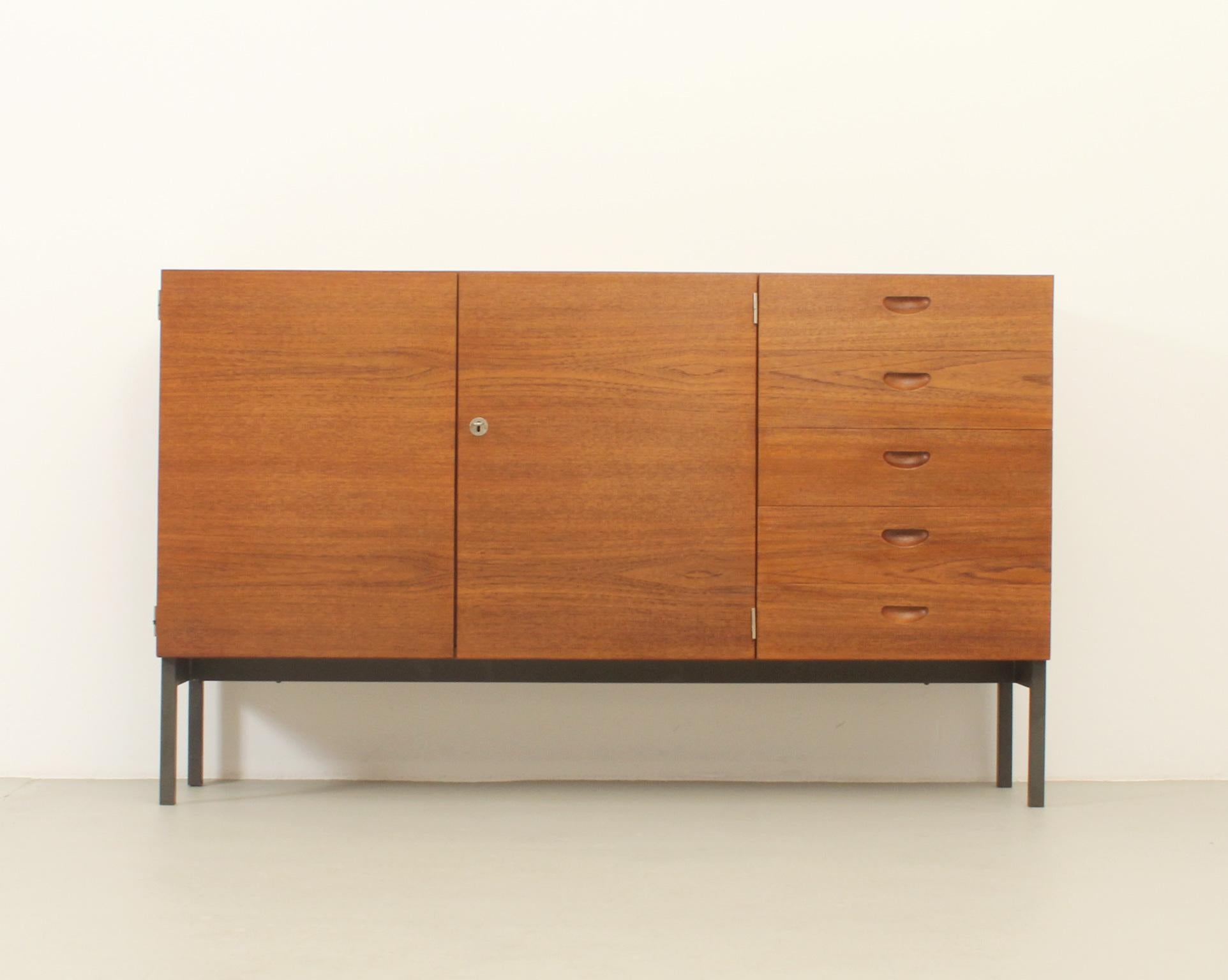 Sideboard designed in 1960s by Herbert Hirche for Christian Holzäpfel, Germany. Teak wood with maple wood interior and black metal base. Two doors with internal shelves and five drawers.