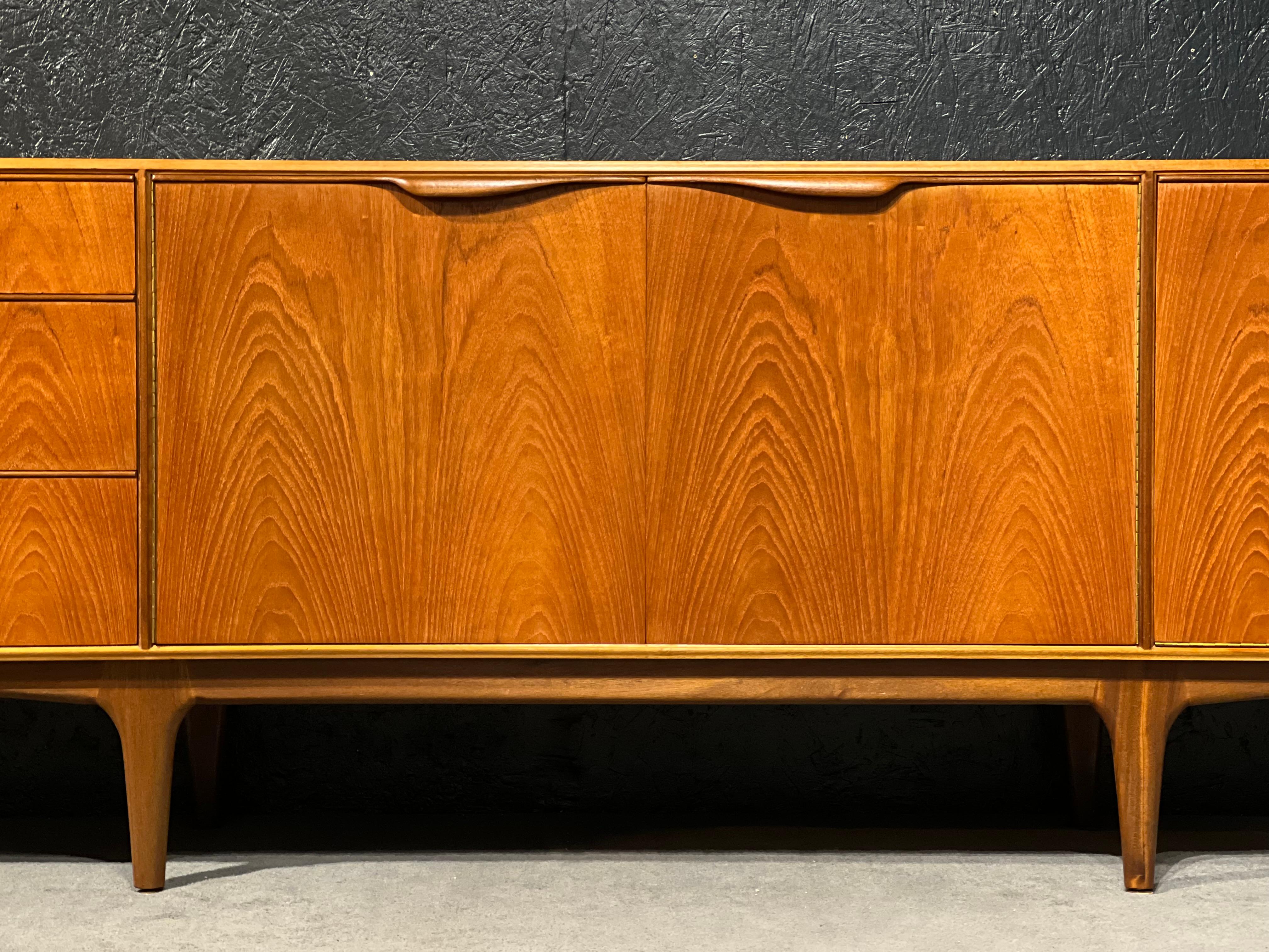 This is a stunning and iconic designs by Tom Robertson for A. H McIntosh Kirkcaldy. This sideboard is well proportionated and light on its feet, sculpted handles add an organic shape to this streamlined design. The cupboard and drawers gave you
