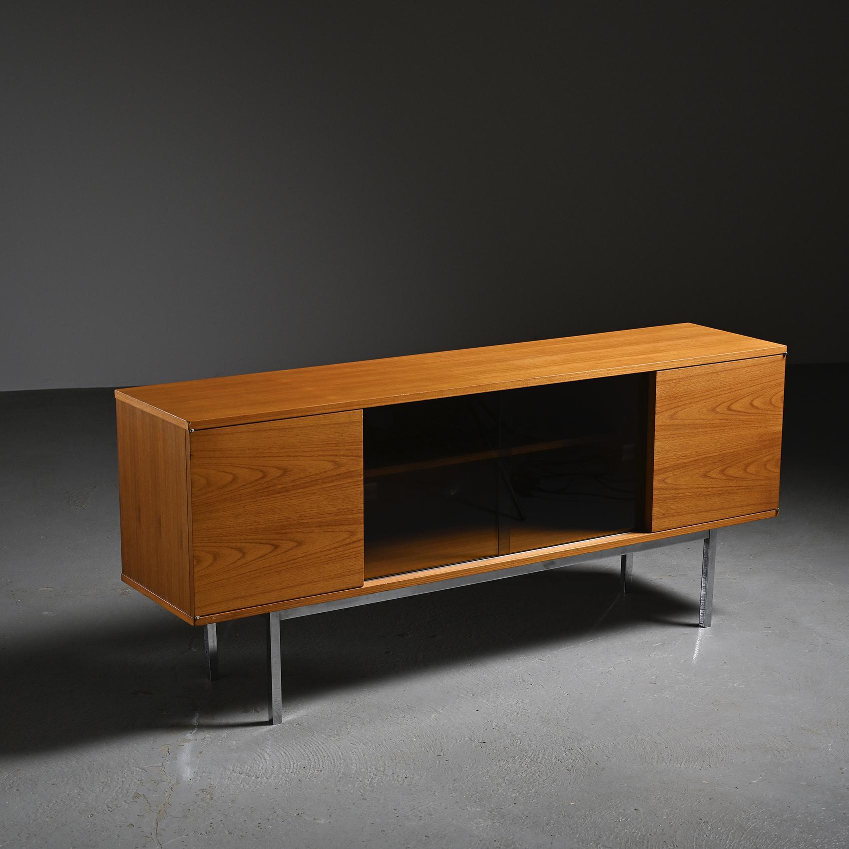 
Published by the Japanese manufacturer Tendo Mokko in the 1960s, this sideboard is crafted from solid teak and teak veneer with a warm and regular grain. It opens with two hinged teak doors on the sides and two central sliding doors in smoked
