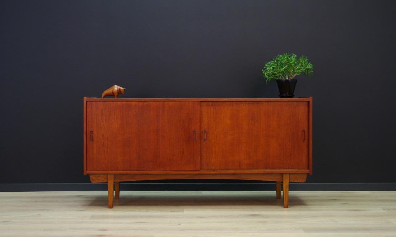 Classic 1960s-1970s sideboard - a minimalistic form finished with teak veneer. Handles and construction made of teak wood. Roomy interior with shelves and a drawer behind the sliding doors. Preserved in good condition (small dings and scratches,