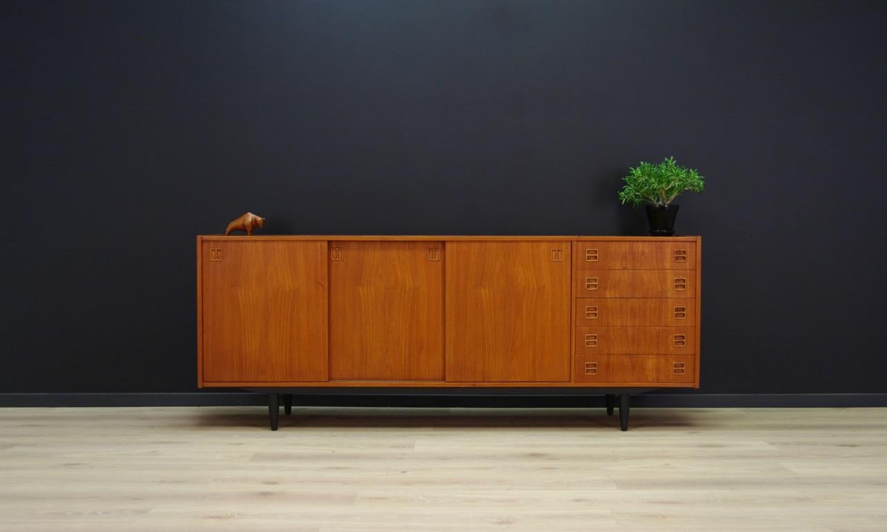 Classic sideboard from the 1960s-1970s, a Minimalistic form finished with teak veneer. Roomy interior with shelves behind the sliding doors. Five external drawers. Preserved in good condition (small bruises and scratches), directly for