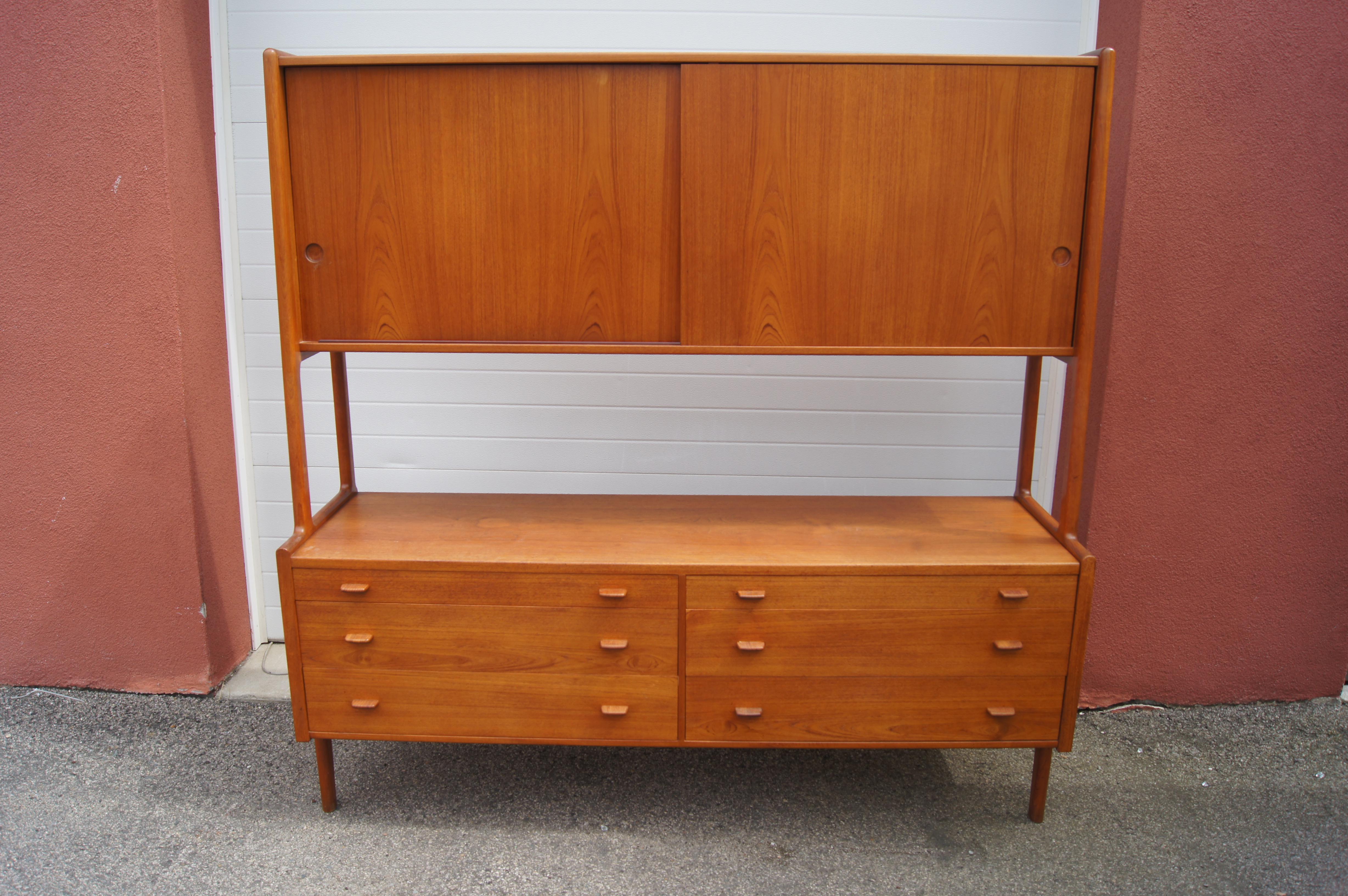 Designed by Hans Wegner for Ry Møbler, this double sideboard exemplifies Danish Modernism. Solidly constructed of oiled teak, the piece features an upper case with sliding doors that open onto adjustable shelving; the lower case houses six roomy