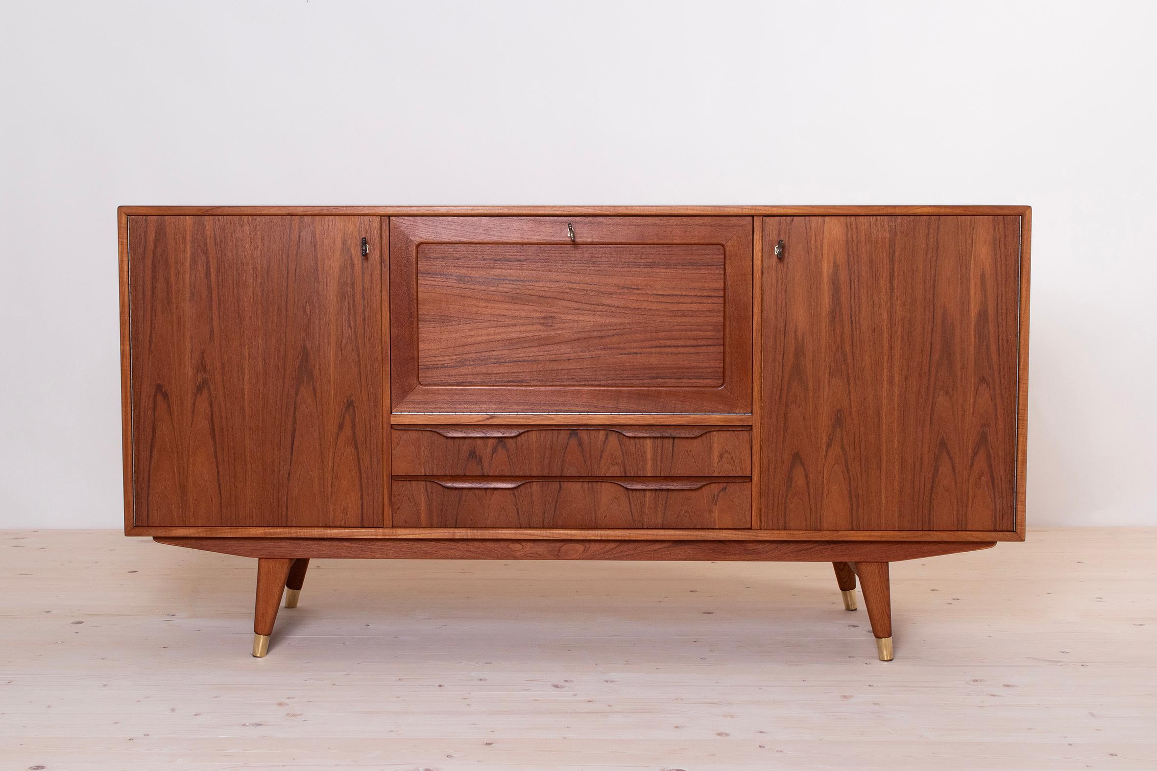 This beautifully designed sideboard comes from Norway and was made around 1960s. It is made of teak wood. It features three storage sections and additionally two spacious drawers in the bottom area. Each section is lockable with a key. In the center