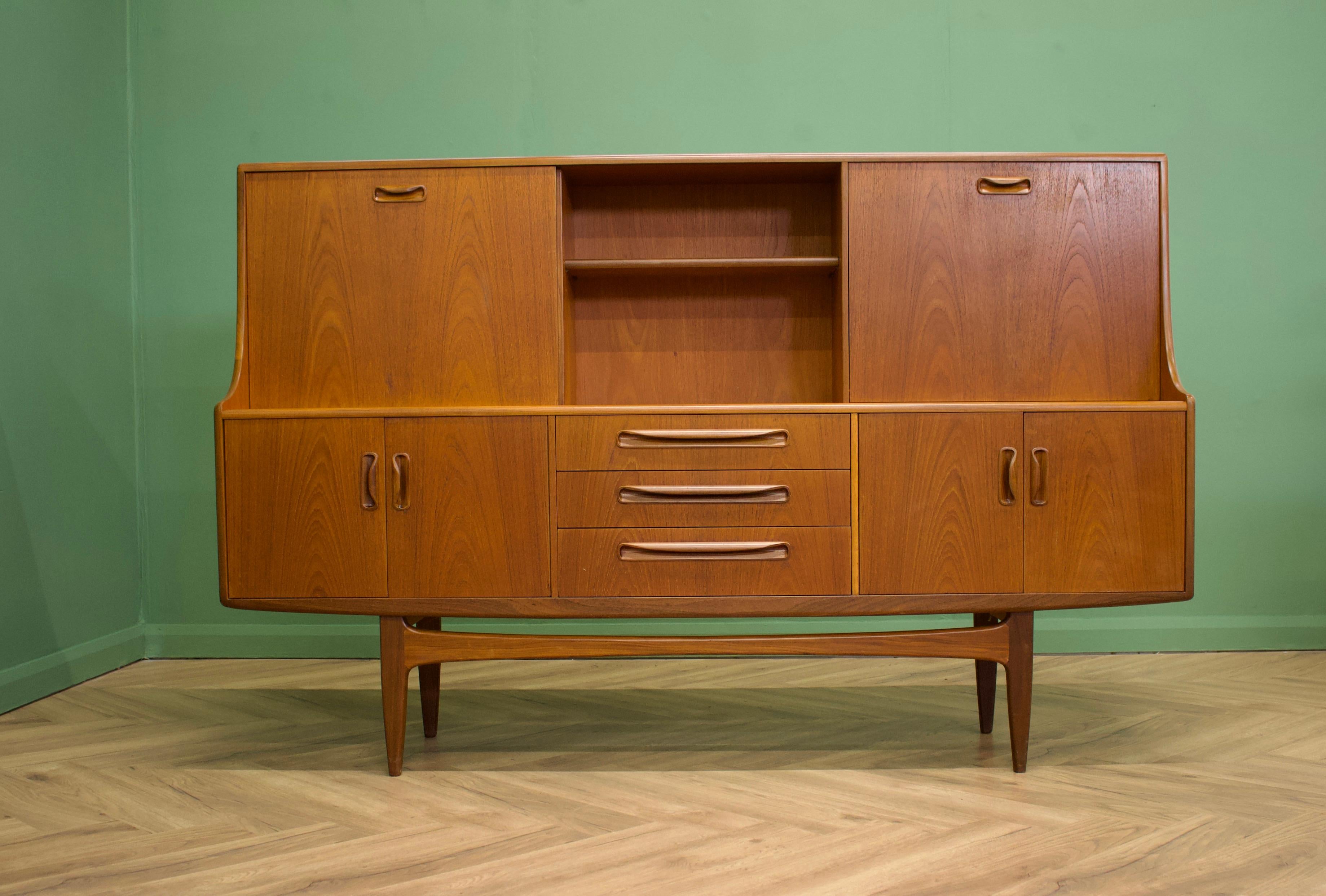 - Mid century modern highboard or sideboard.
- Featuring a pull down drinks cabinet and a sliding cupboard door.
to the top.
- Manufactured by G Plan in the UK.
- Made from teak and teak veneer.