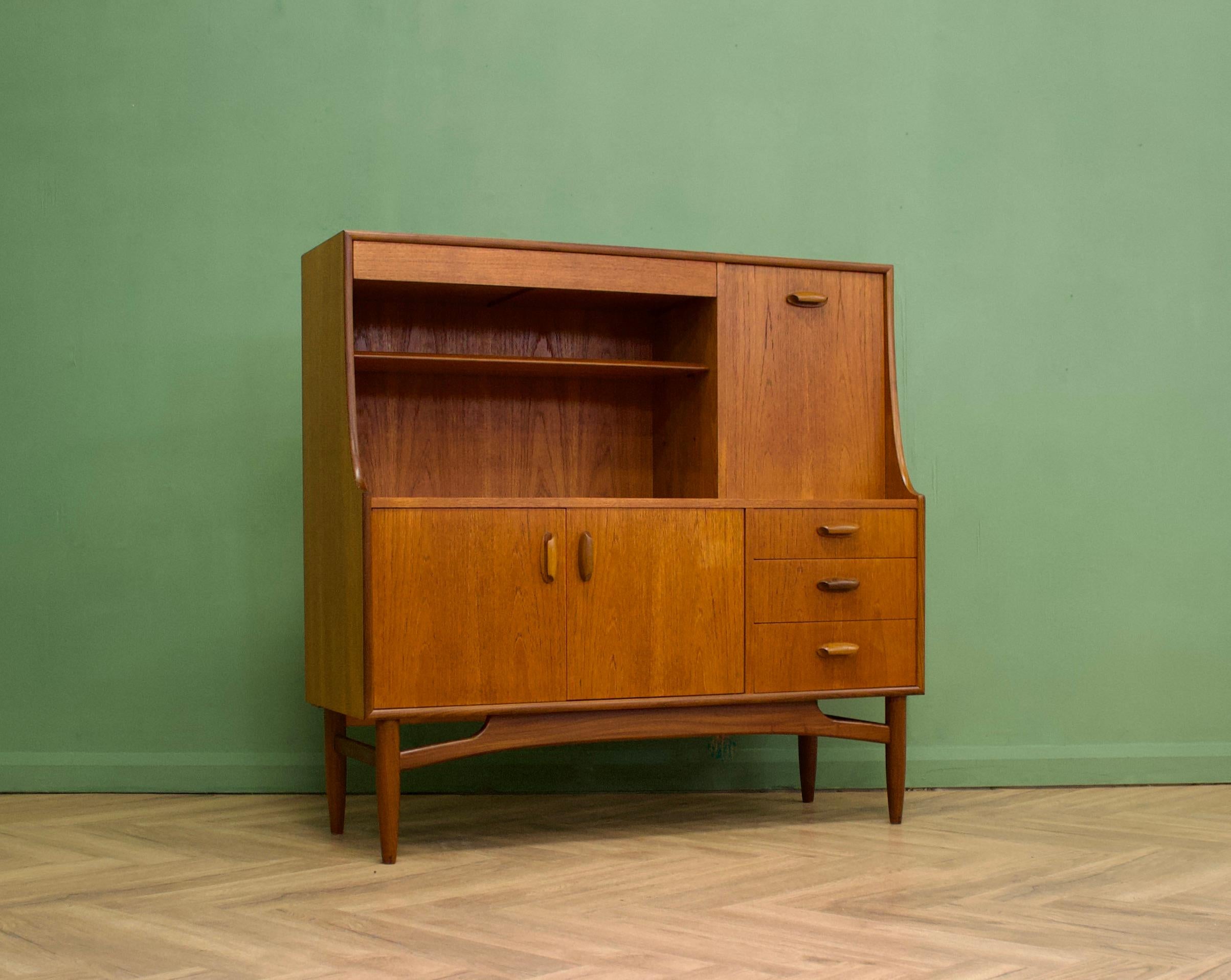 - Mid century modern highboard or sideboard
- Featuring a pull down drinks cabinet, a cupboard, three drawers and shelves
- Manufactured by G Plan in the UK
- Made from teak and teak veneer