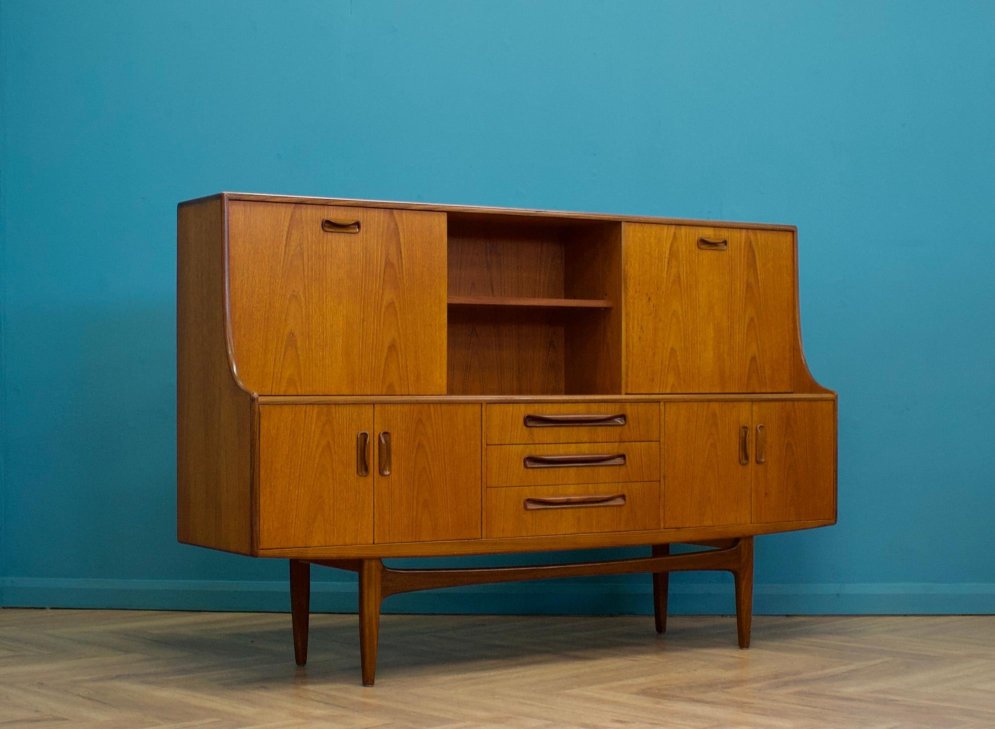 - Mid century modern highboard or sideboard.
- Featuring a pull down drinks cabinet and a sliding cupboard door.
to the top.
- Manufactured by G Plan in the UK.
- Made from teak and teak veneer.