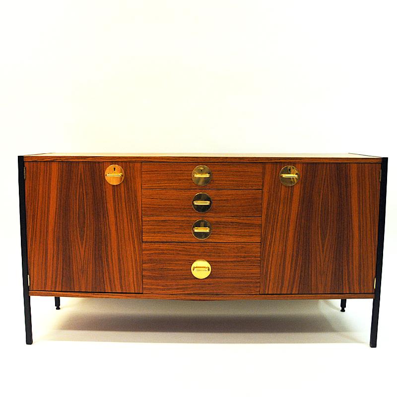Vintage teak sideboard from the Triva modul series by Erik Herløw for Nordiska Kompaniet 1960s, Sweden. The sideboard has lovely brass details and the design is clean and Classic with a black steel frame around.
Inside there are two cabinets and