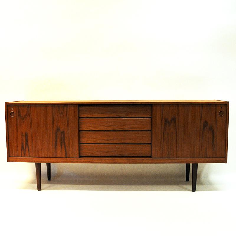 Lovely teak sideboard with beautiful patterns in the wood all-over the sideboard body. Produced by Gustav Bahus, Norway, 1960s. This vintage sideboard has two sliding doors and four drawers in the middle in which are hidden when the doors are open.