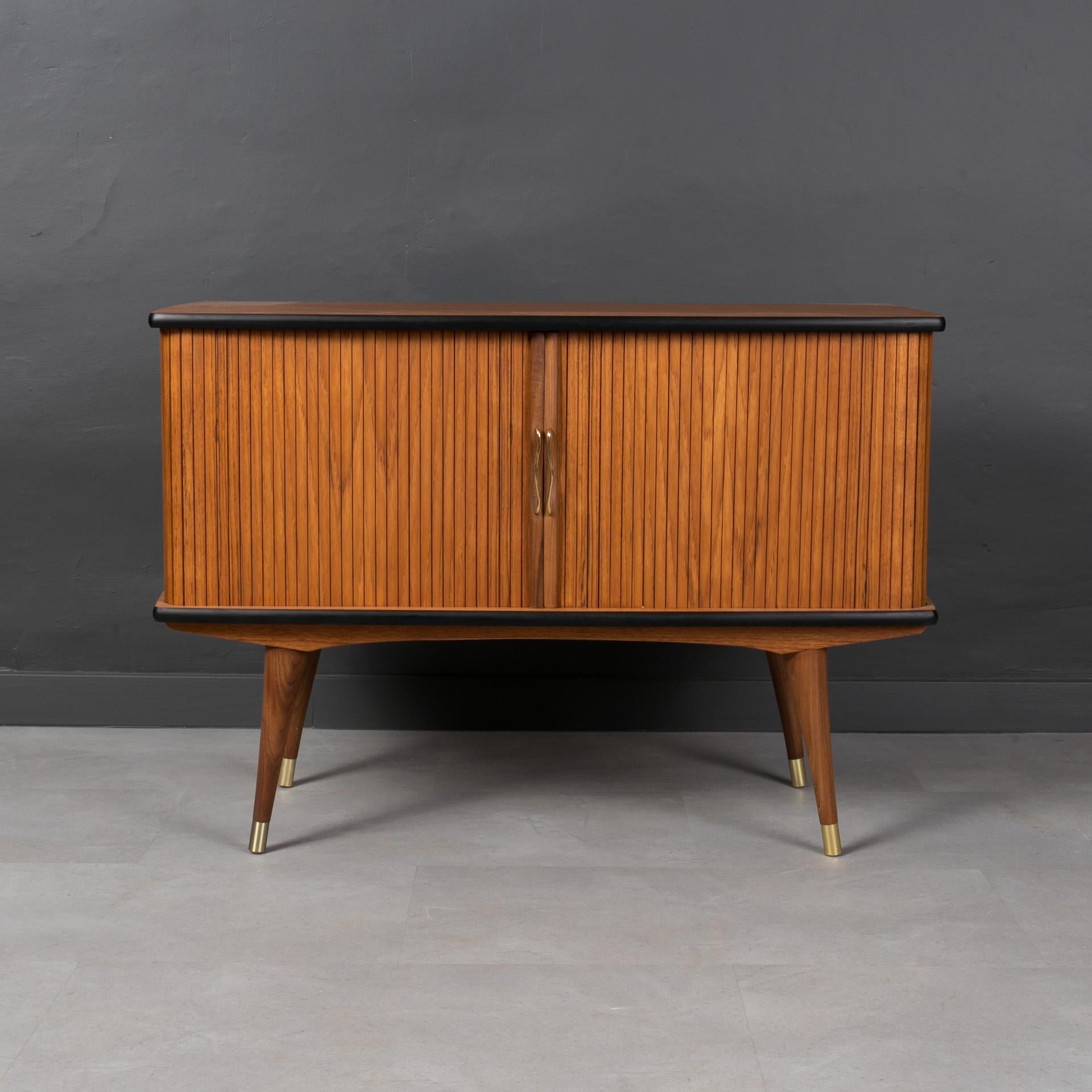 This teak sideboard comes from Norway and was made around 1960s. It features very smart solution of tambour doors that reveal the main storage section. Tambour doors work easily. The chest is set on a solid teak frame, all four legs are finished