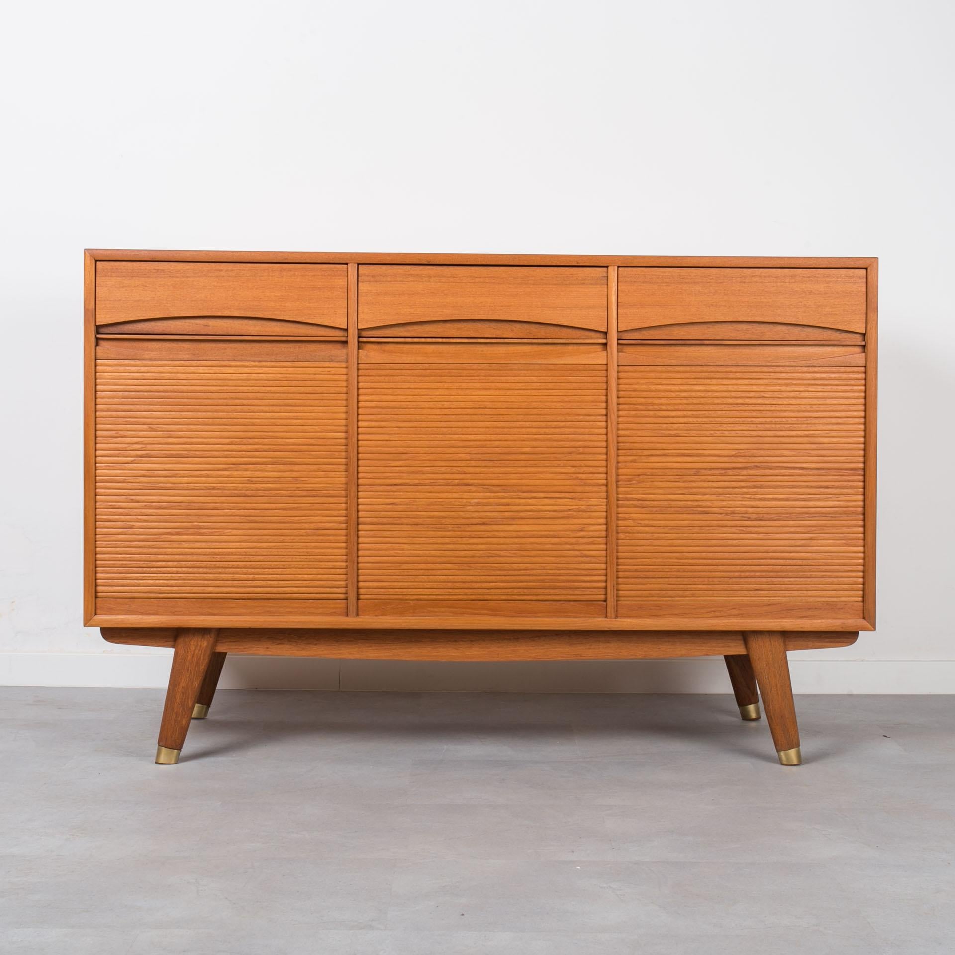 This teak sideboard comes from Norway and was made around 1960s. It features three storage sections, each one with tambour doors rolling down to reveal the storage space. In the middle section you will find 4 practical drawers, while left and right